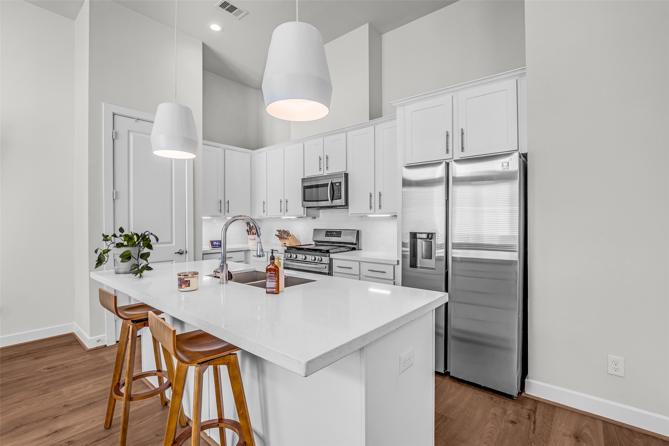 It includes an island with a built-in sink, providing additional workspace for meal preparation and a convenient breakfast bar for casual dining.