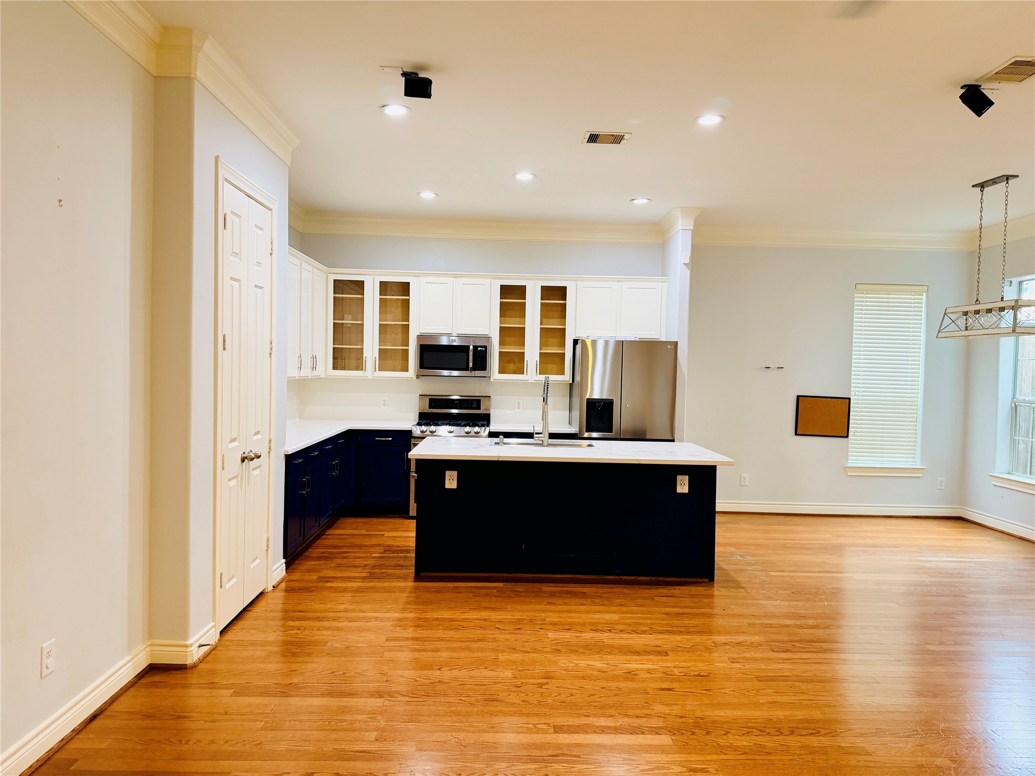 Different angle of the kitchen features white cabinetry with glass-front upper cabinets, stainless steel appliances, a gas range, and abundant storage.