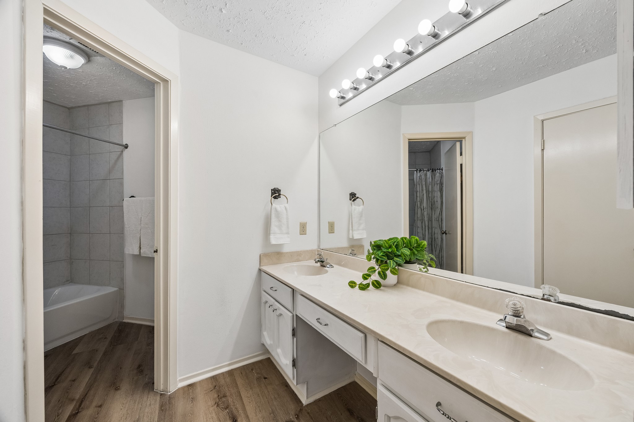Primary ensuite bathroom provides LVP in wet spaces, double sinks, and Hollywood lighting.