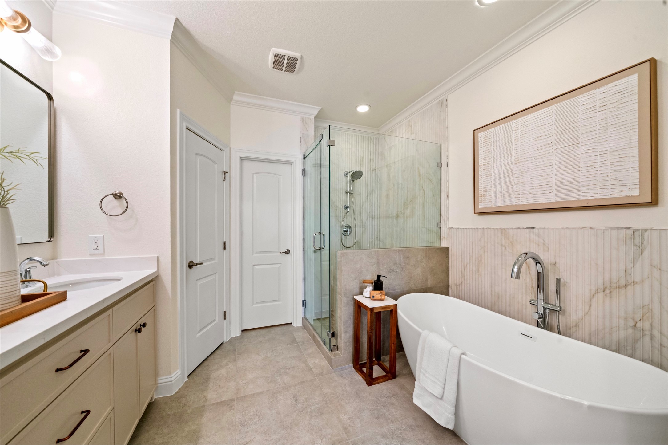 The completely updated primary bath with soaking bath, separate shower, quartz counters, framed mirror and sleek fixtures and hardware.