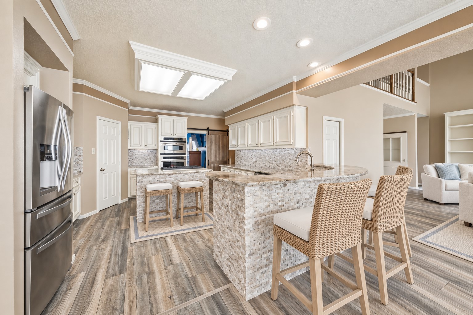 THE OPEN KITCHEN FEATURES EXTENSIVE COUNTER SPACE, BREAKFAST-BAR SEATING, STAINLESS STEEL APPLIANCES, AND DURABLE WOOD-LOOK FLOORING. **Virtually Staged.