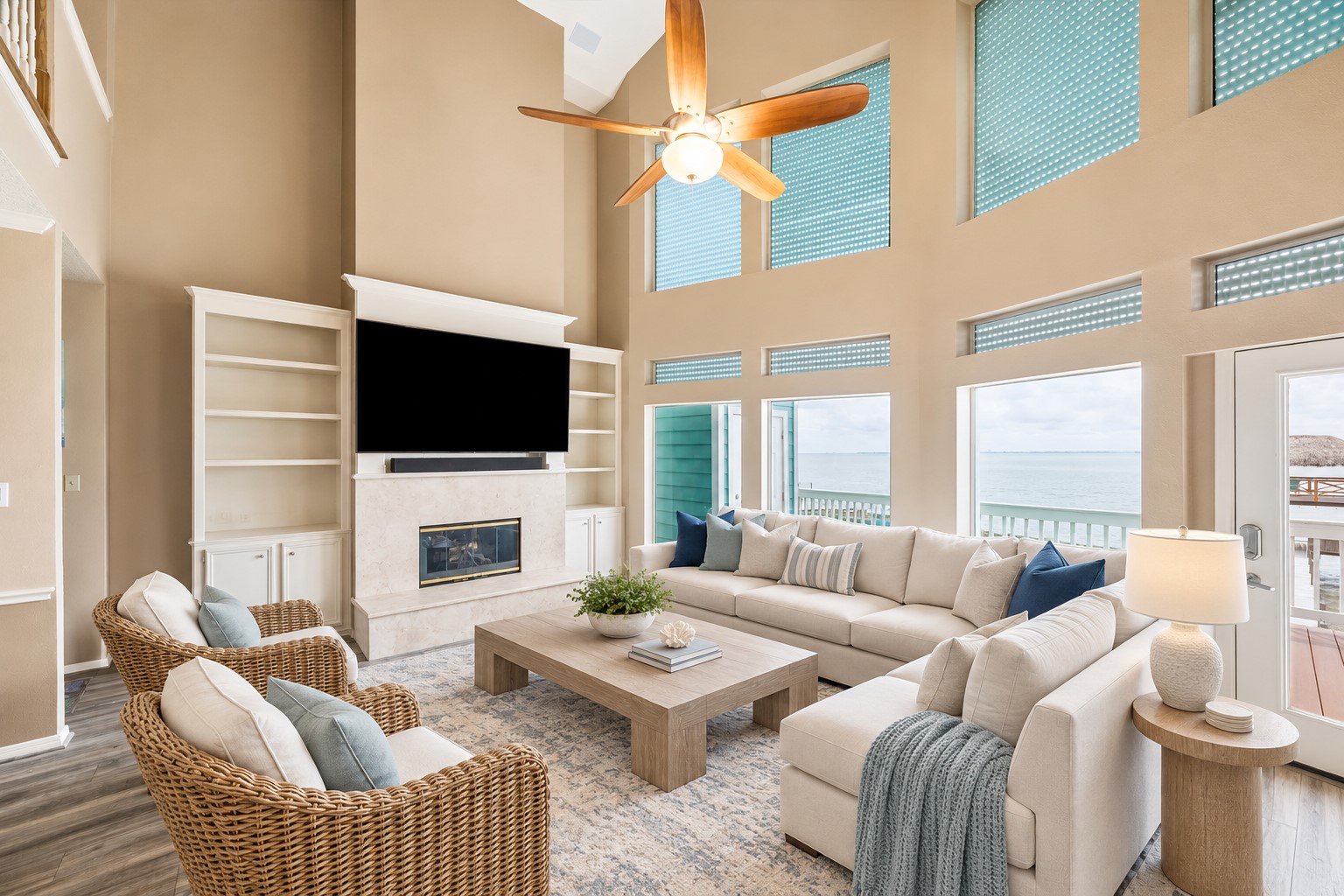 THE TWO-STORY FAMILY ROOM FEATURES A FIREPLACE, BUILT-IN STORAGE, SOARING WINDOWS, AND DIRECT BALCONY ACCESS WITH WATER VIEWS. **Virtually Staged