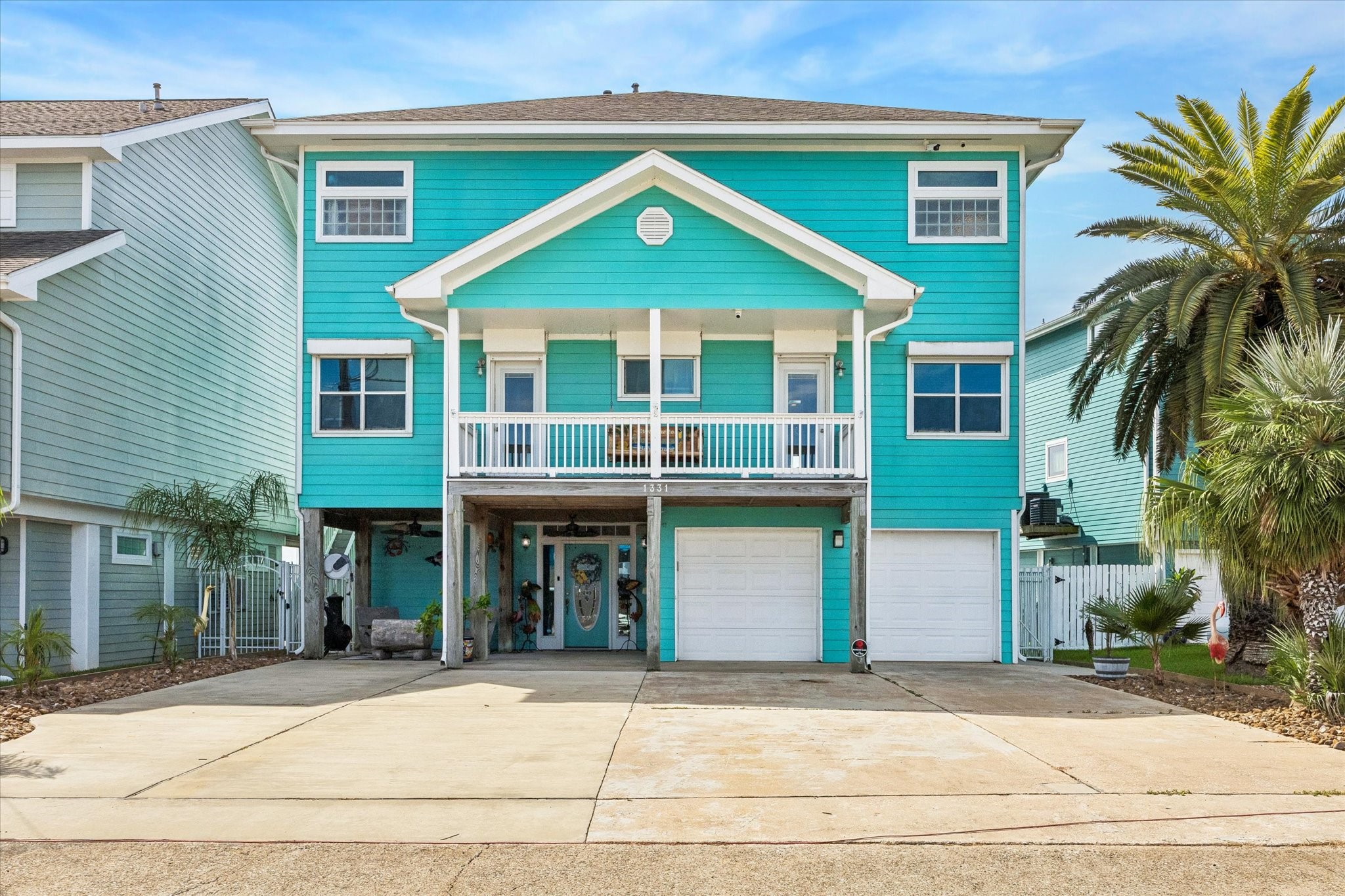 ELEVATED CONSTRUCTION, A COVERED FRONT BALCONY, AND TWO GARAGE BAYS COMPLEMENT THE HOMES COASTAL EXTERIOR.