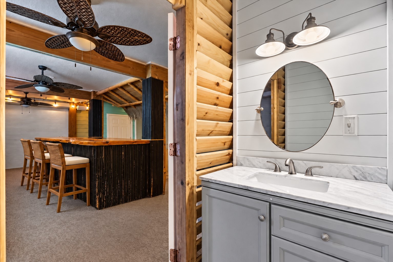 CONVENIENT OUTDOOR BATHROOM LOCATED JUST OFF THE TIKI BAR, FEATURING A STONE COUNTERTOP, SHIPLAP ACCENT WALL, AND EASY PATIO ACCESS. **Virtually Staged.
