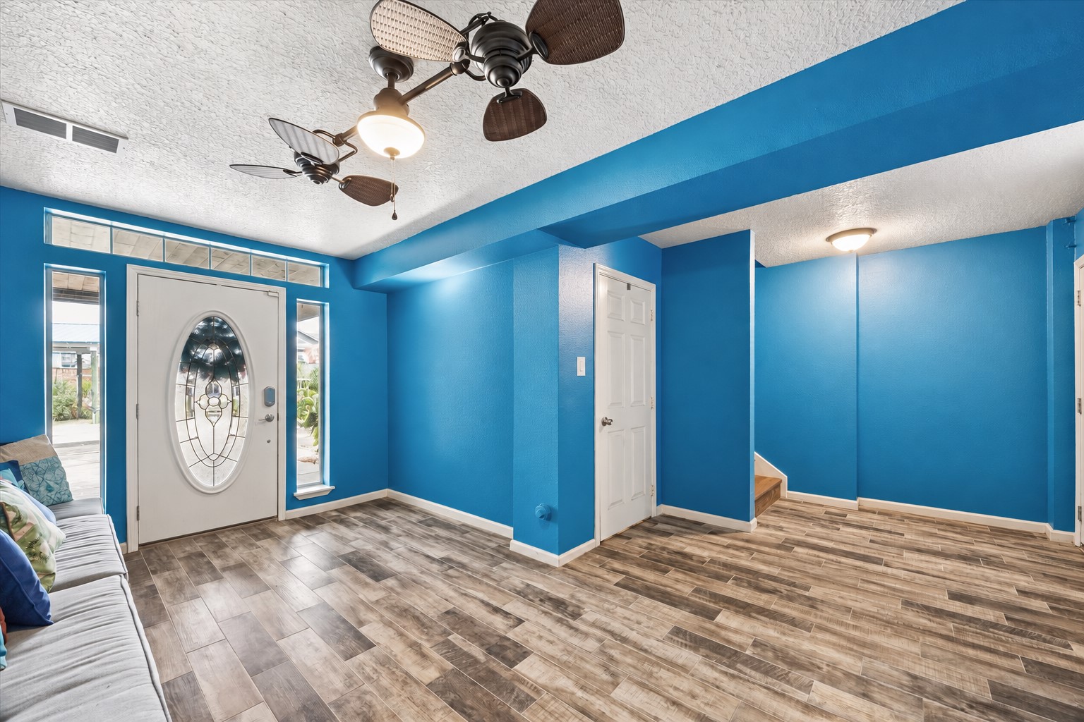 THE SPACIOUS ENTRY FEATURES WOOD-LOOK TILE FLOORING, TRANSOM WINDOWS, SIDELIGHTS, AND EASY ACCESS TO THE UPPER LEVEL.