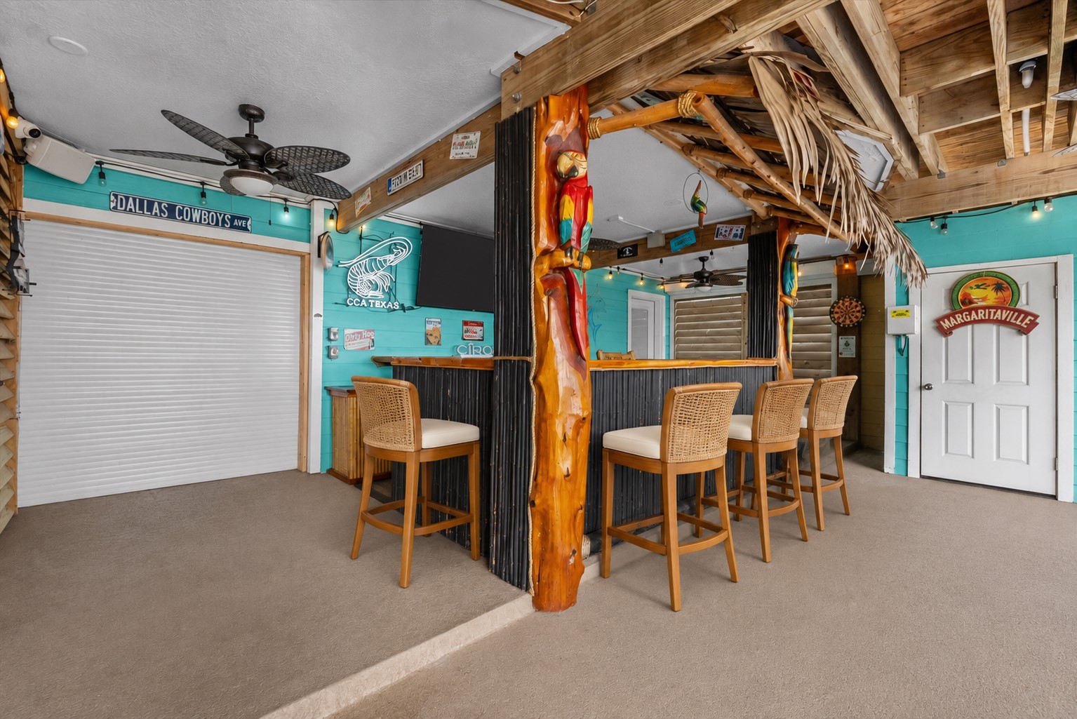 COVERED TIKI BAR AREA WITH WRAPAROUND COUNTER SPACE, CEILING FANS, ROLL-DOWN SHUTTERS, AND DIRECT ACCESS TO THE OUTDOOR ENTERTAINING AREAS. **Virtually Staged.
