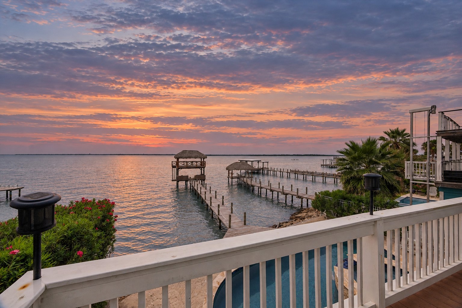 THE PRIVATE PIER EXTENDS INTO OPEN WATER AND LEADS TO A TWO-LEVEL PALAPA-COVERED DOCK.