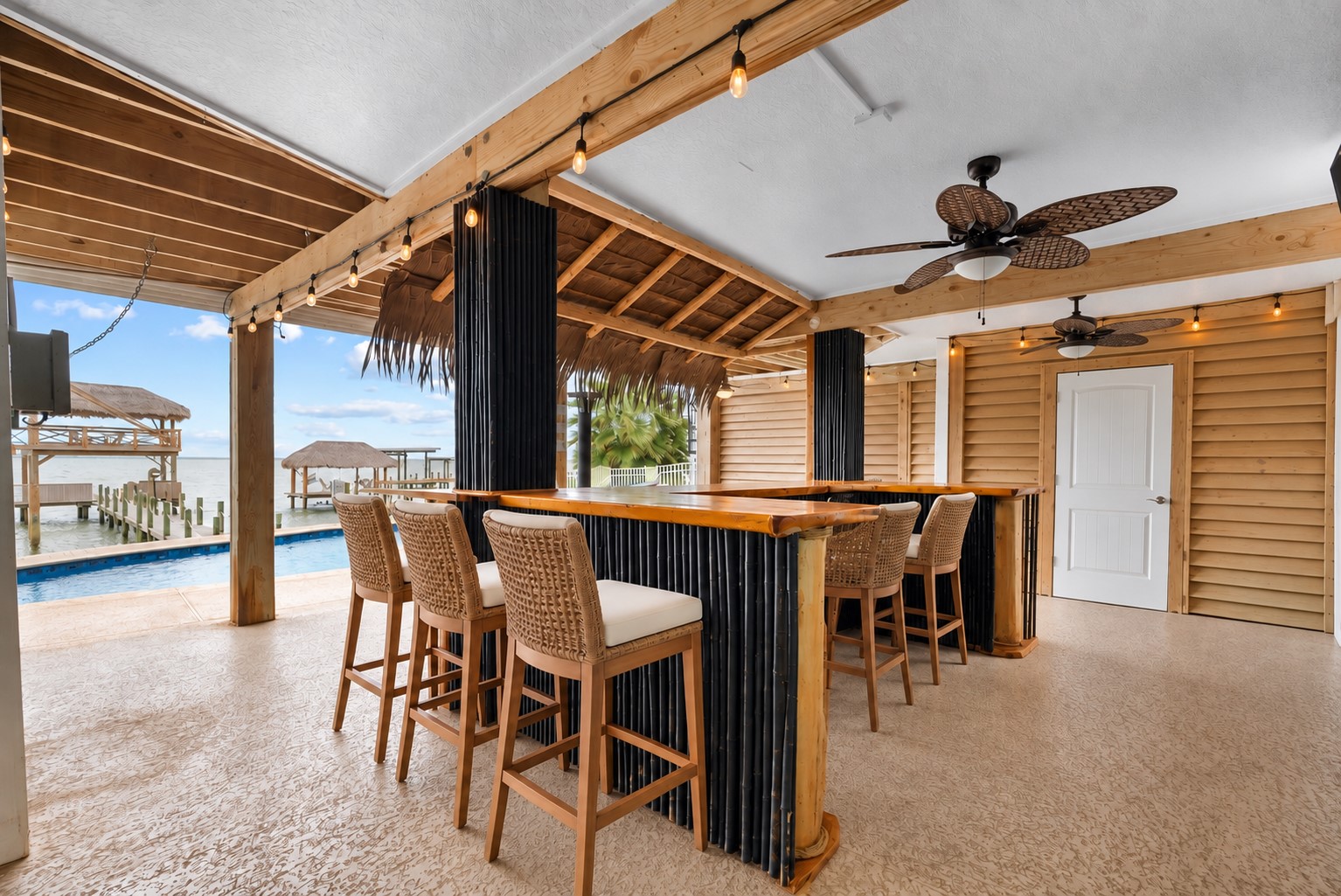 COVERED TIKI BAR WITH WRAPAROUND COUNTER SPACE, CEILING FANS, ROLL-DOWN SHUTTERS, AND DIRECT ACCESS TO THE OUTDOOR ENTERTAINING AREAS.**Virtually Staged.