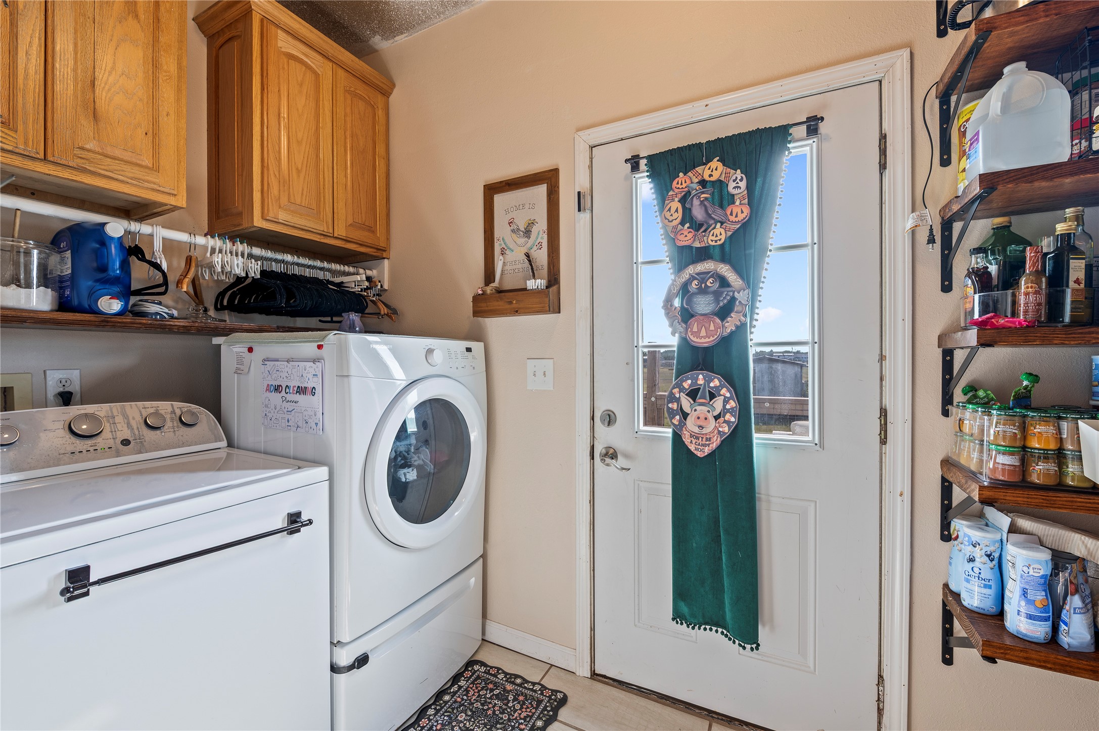 Tiled utility room area with washer/dryer, wood cabinets, and back deck/patio access.