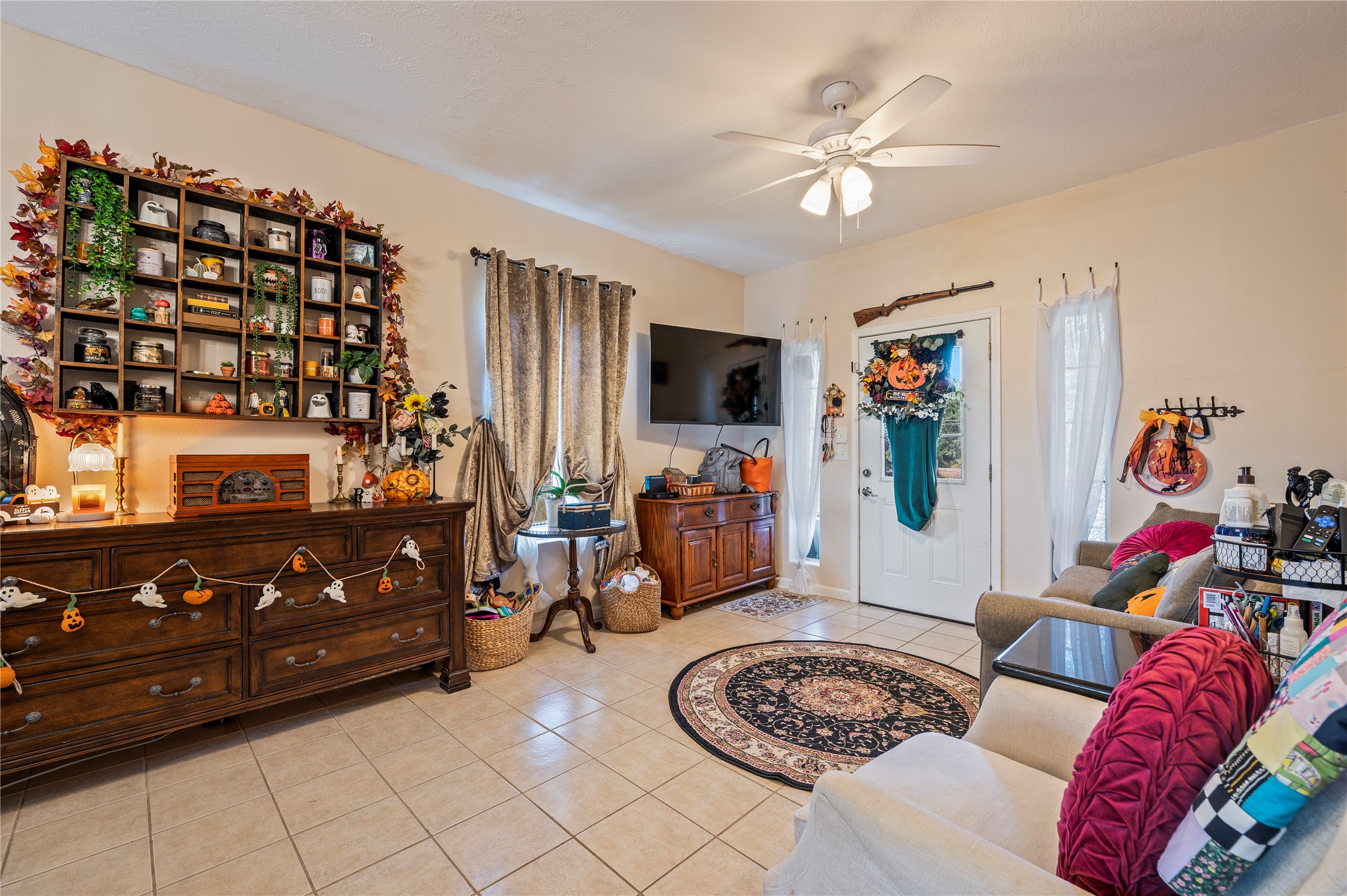 Tiled living room space with ceiling fan fixture.