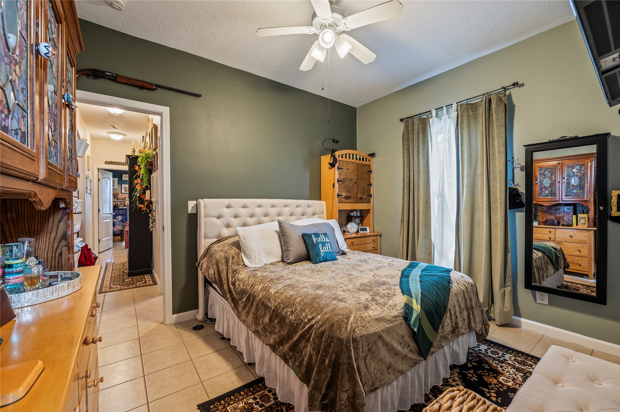 Spacious primary bedroom with tile flooring and ceiling fan fixture.