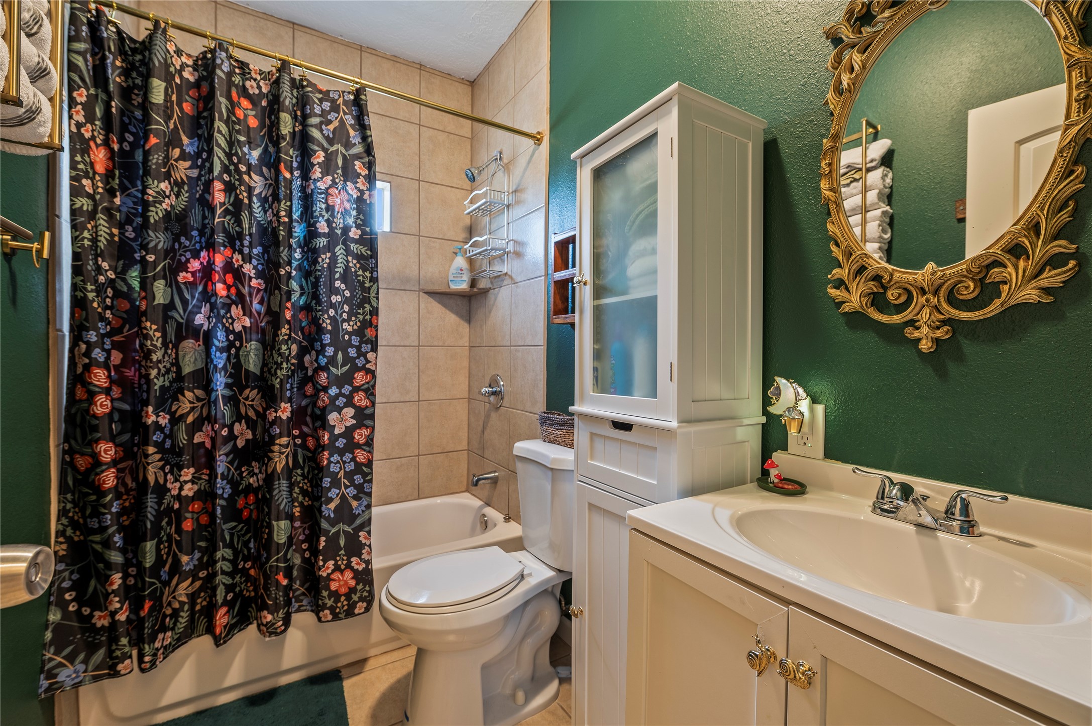 Full sized spare bath with vanity sink, accent mirror, and tiled shower/tub combo.