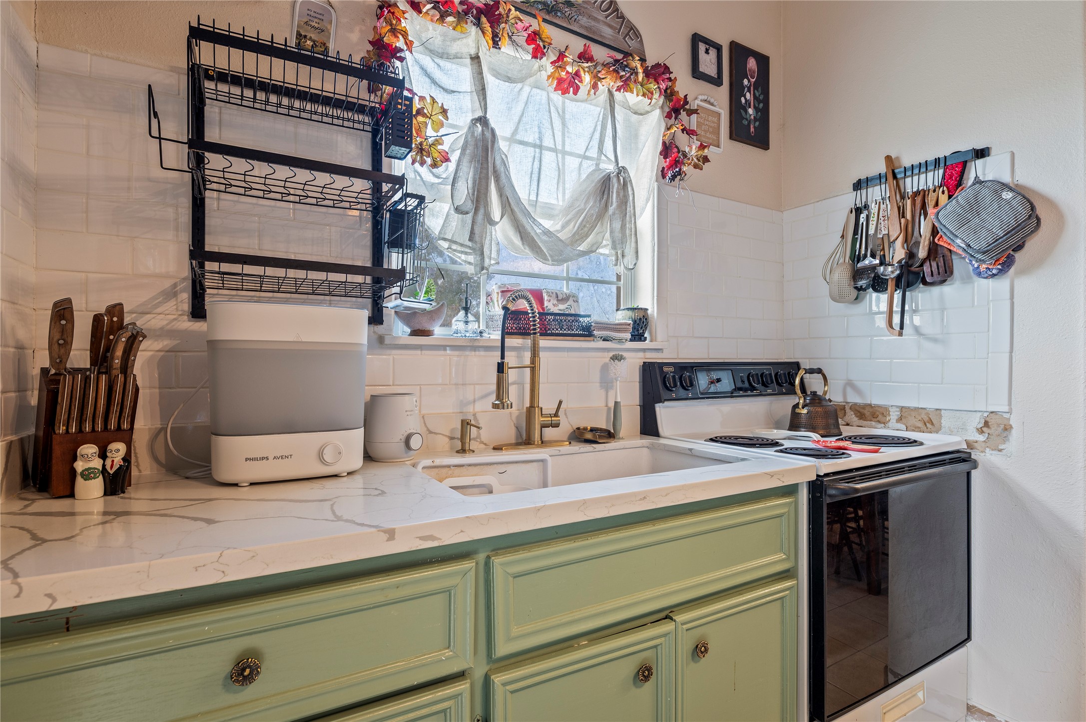 Ample counter top space with large sink, over sink window, and electric range.