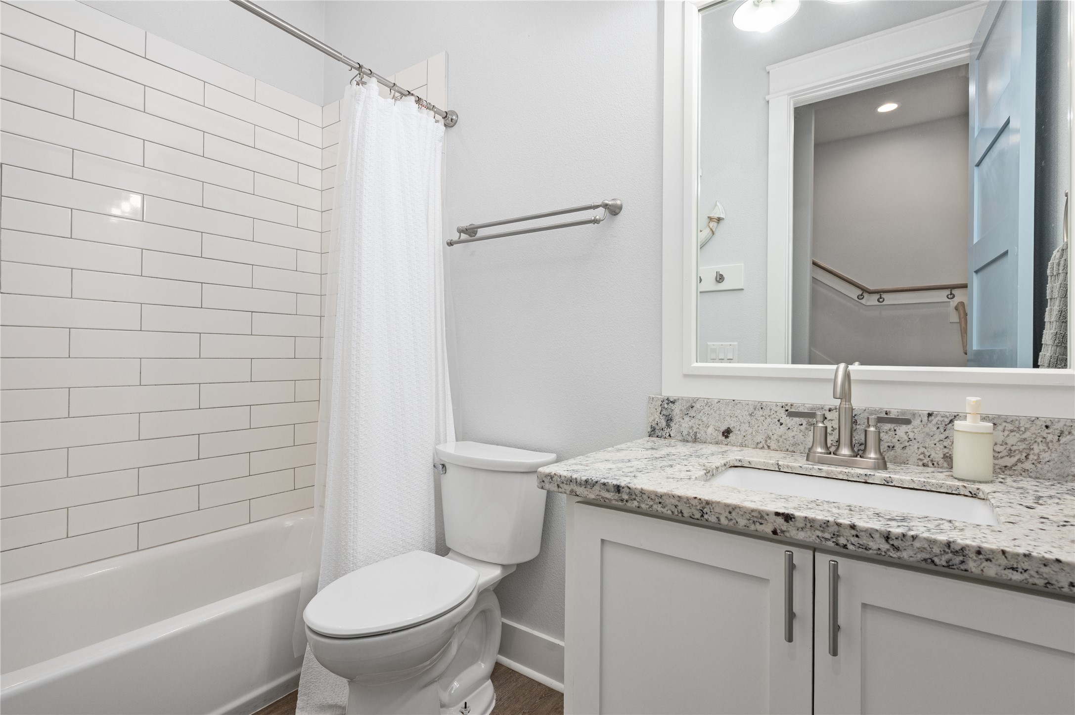 A bright full bath keeps mornings simple with a granite-topped vanity and subway-tile tub and shower surround.