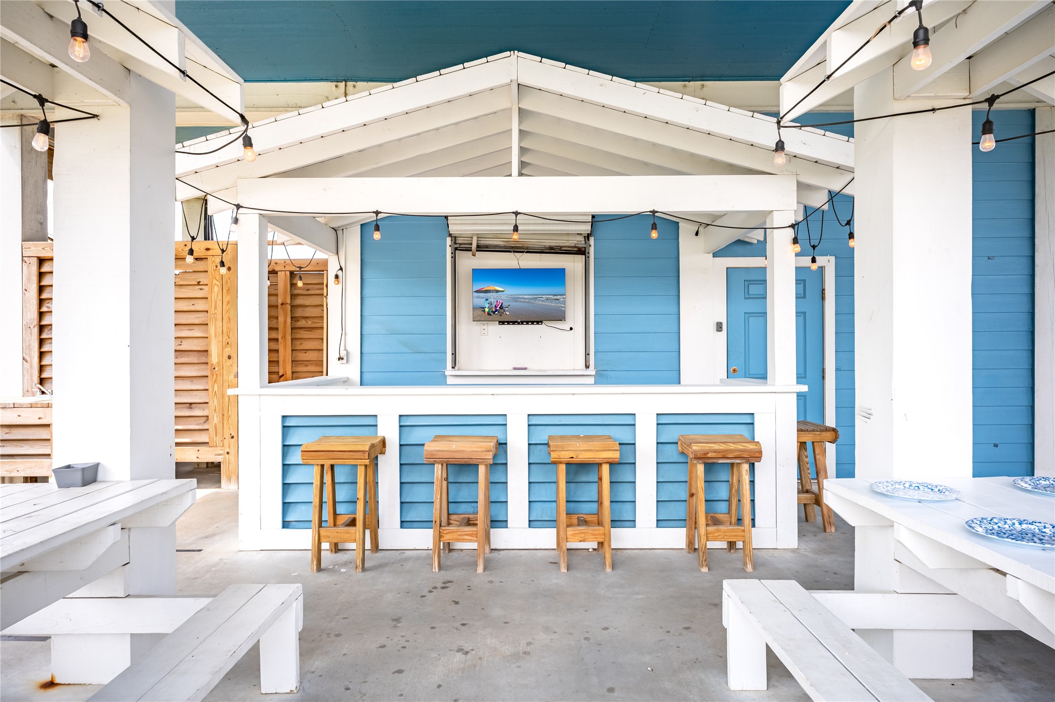 Weekends at home mean gathering around your covered outdoor bar, catching the game, and enjoying meals together under the string lights.