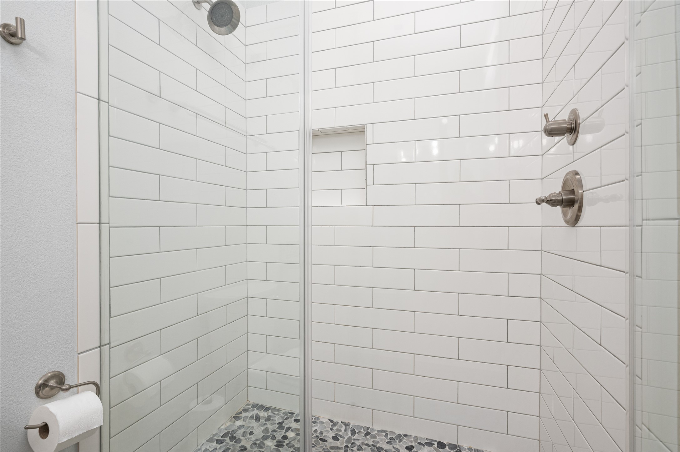 Start each day in your sleek walk-in shower, finished with crisp subway tile, a pebble-style floor, and a convenient built-in niche.