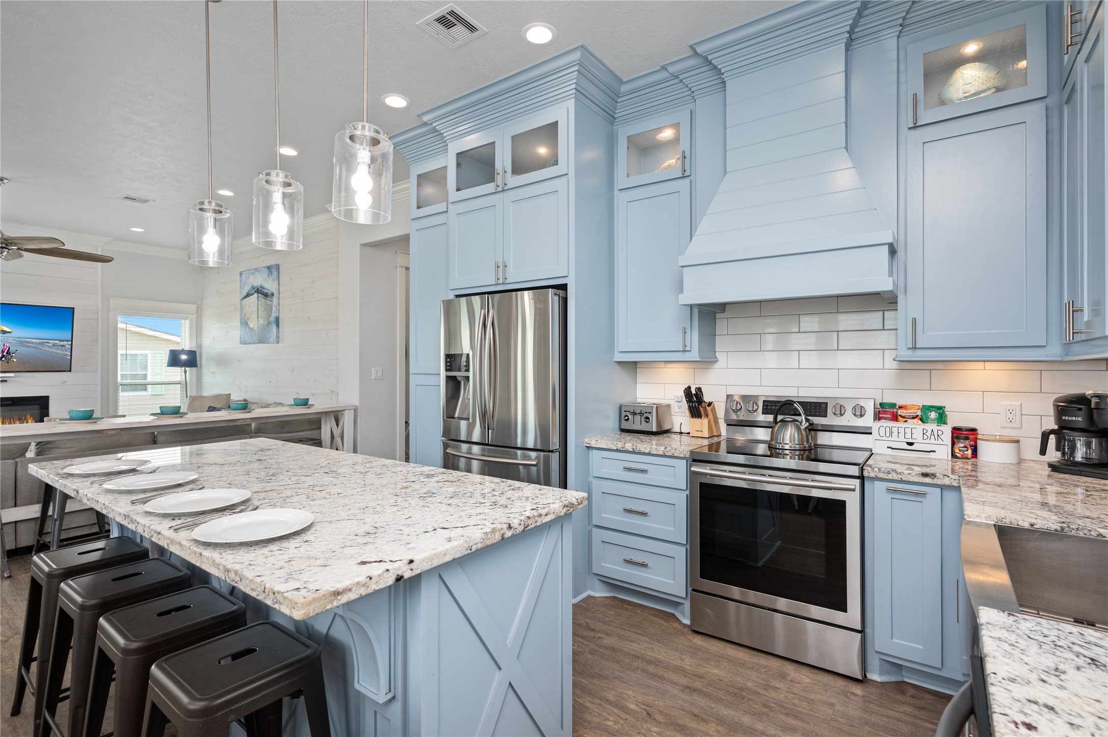 Your coastal-inspired kitchen pairs soft blue cabinetry with granite countertops, stainless appliances, and a statement range hood for a polished finishing touch.