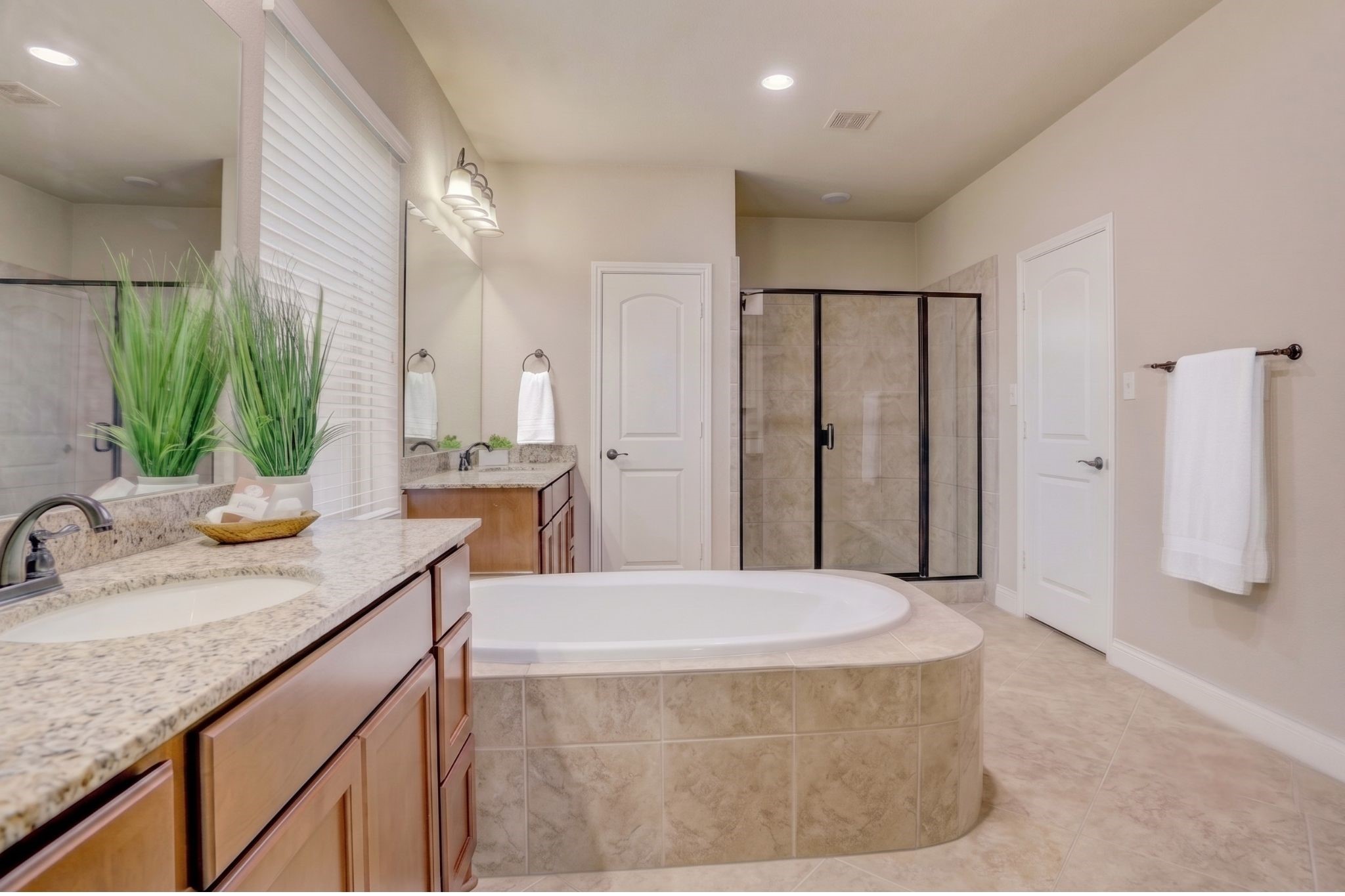 Unwind in the spacious primary bath featuring dual vanities, a relaxing soaking tub, separate walk-in shower, and generous storage designed for everyday comfort.