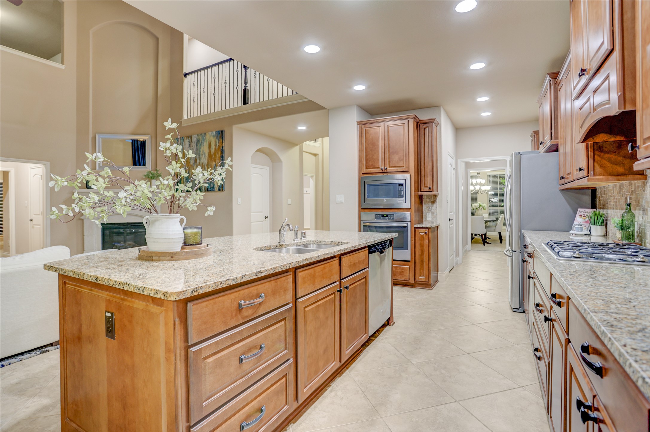 A beautifully appointed kitchen combines timeless finishes with exceptional functionality, featuring rich wood cabinetry, granite countertops, stainless steel appliances, a gas cooktop, and a spacious island designed for gathering and entertaining.