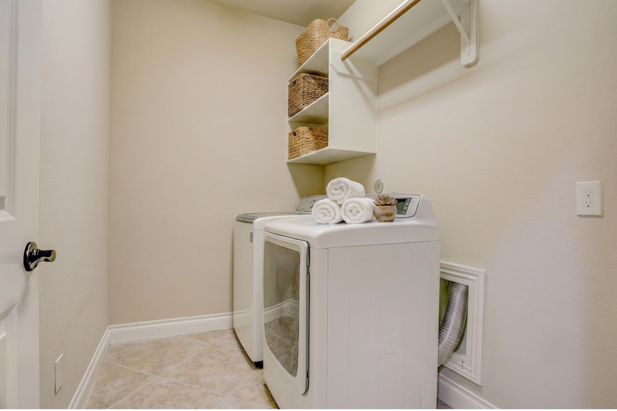 Spacious utility room with built-in shelving, ample storage, and enough room to accommodate a second refrigerator or freezer, adding everyday convenience and extra storage for busy households.