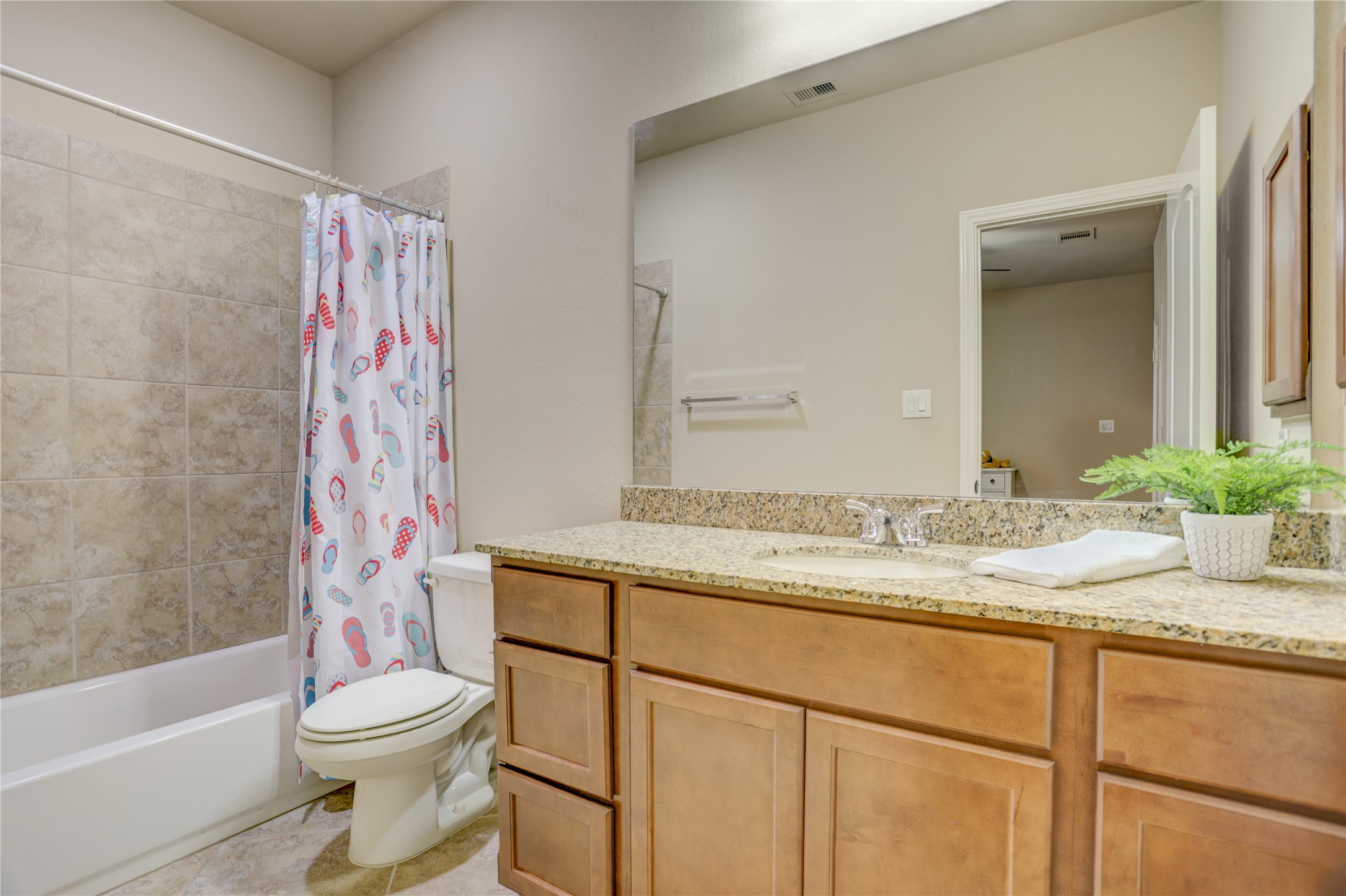 The private downstairs guest suite includes its own en suite bathroom with a granite vanity and a tub/shower combination, offering comfort and convenience for overnight guests or multi-generational living.