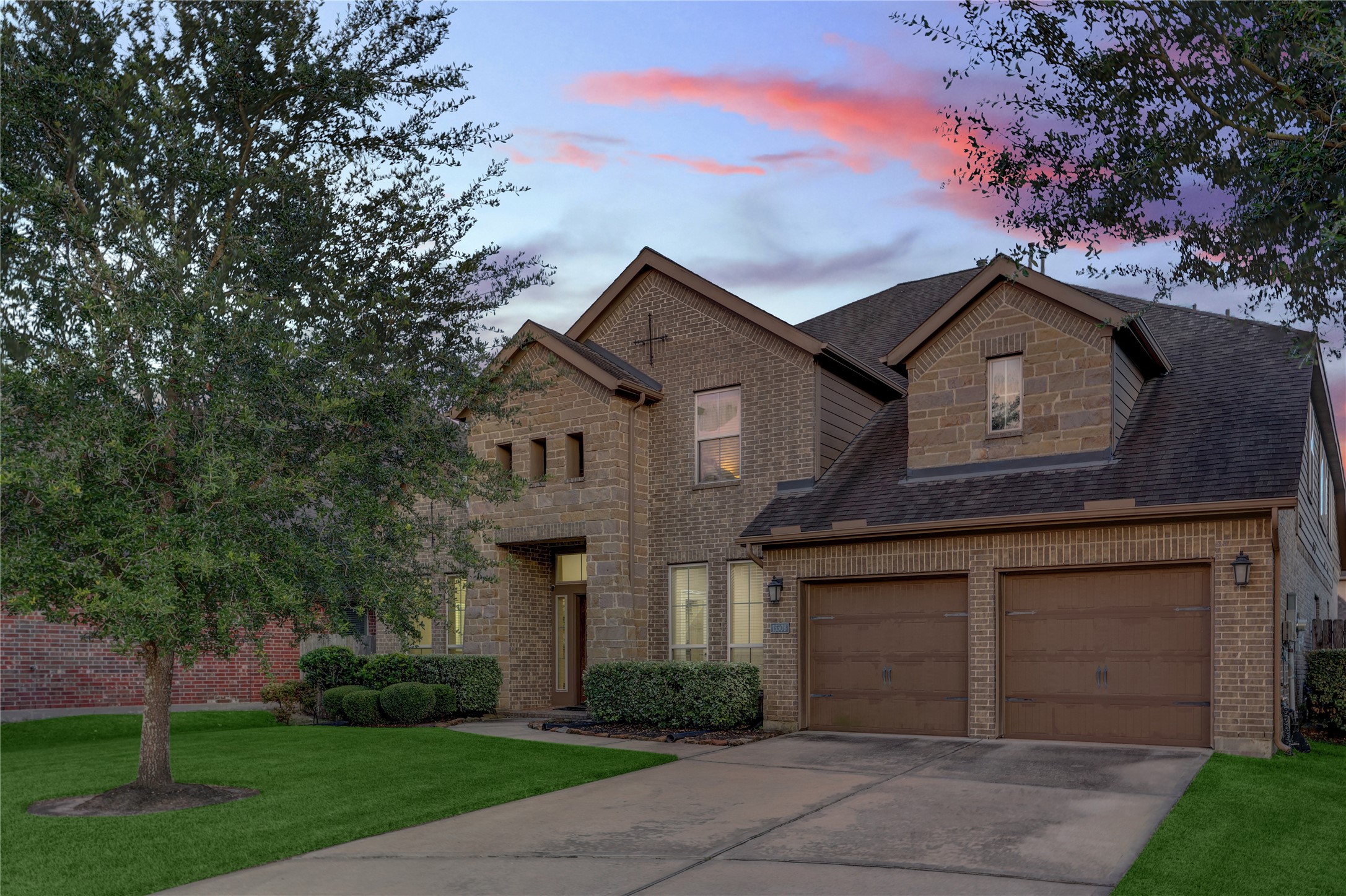 Beautiful brick and stone exterior featuring a covered front porch, manicured landscaping, and a 3-car garage with ample parking and storage.