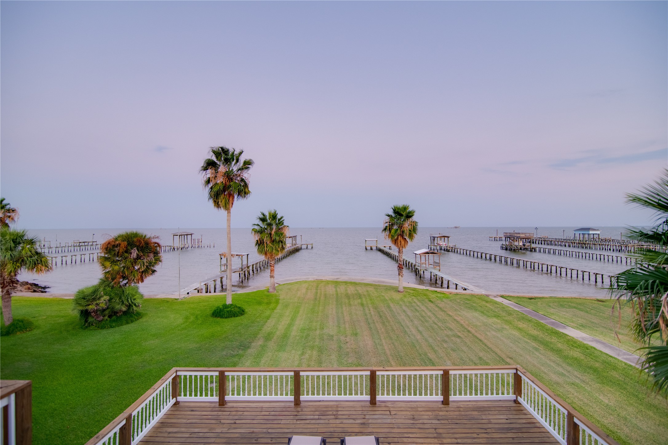 This large yard opens up to a stunning view of the bay, bordered by a sturdy concrete bulkhead that ensures both safety and durability along the waters edge.