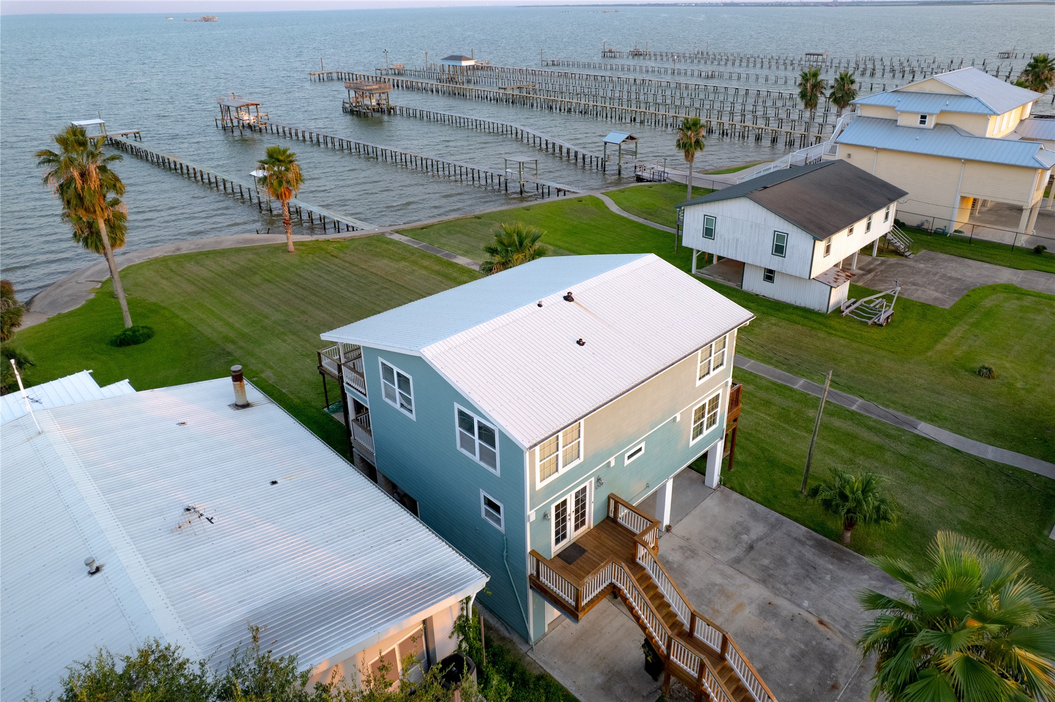 From above, a drone captures a stunning coastal paradise, where sparkling blue waters meet sandy shorelines dotted with charming homes.