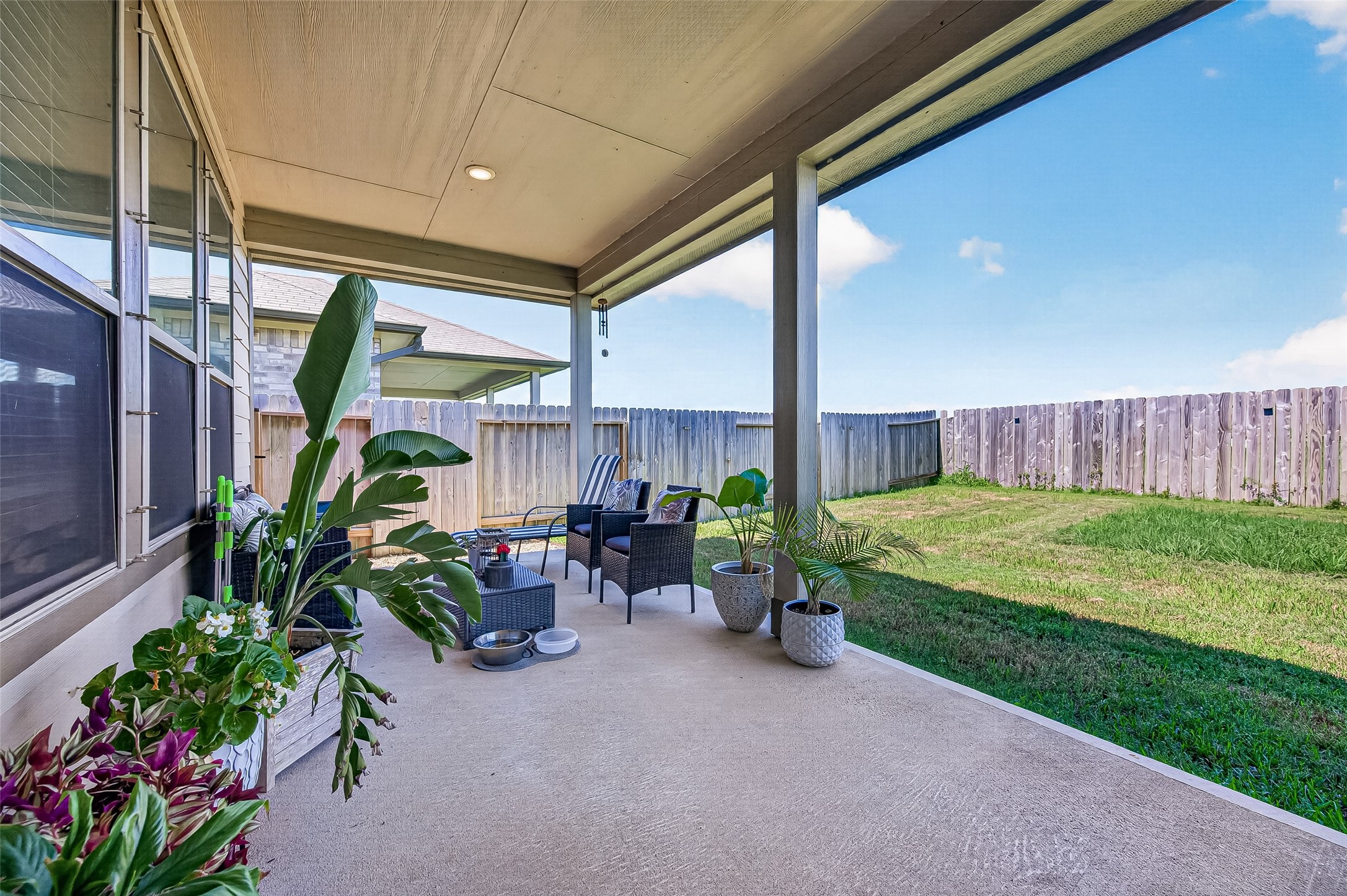 Spacious covered patio perfect for outdoor relaxation, surrounded by a lush, fenced backyard ideal for privacy and leisure.