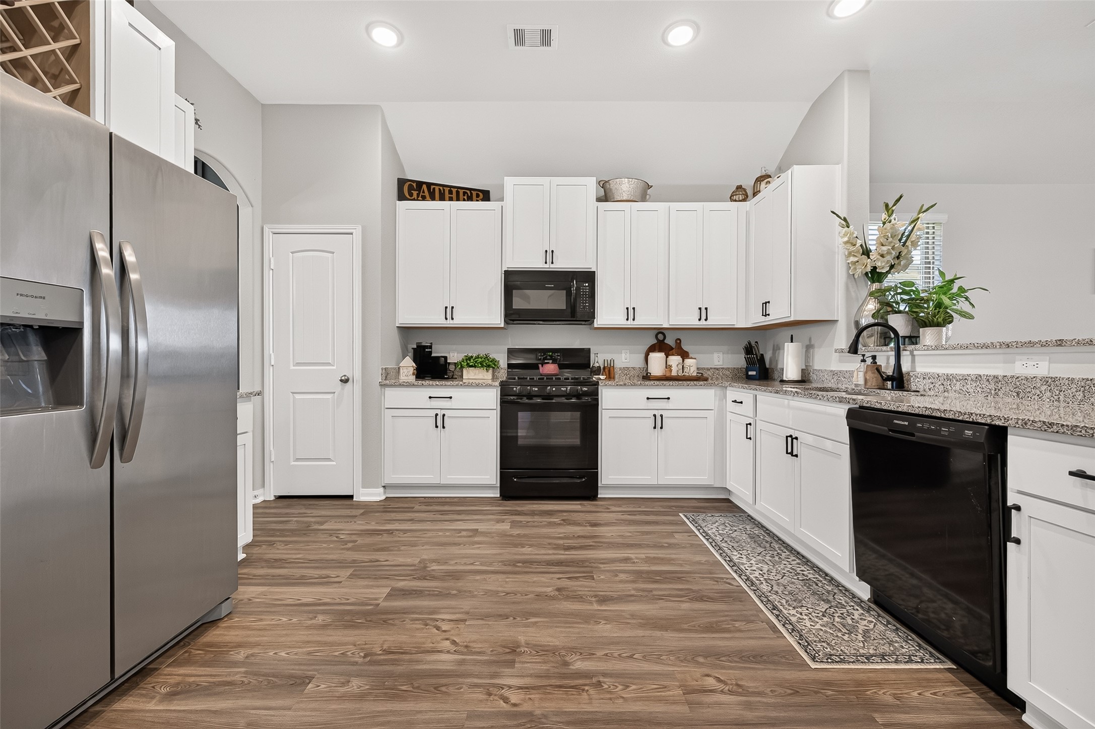 Modern kitchen featuring sleek stainless steel appliances, elegant white cabinetry, and beautiful wood flooring, creating a warm and inviting space for cooking and entertaining.