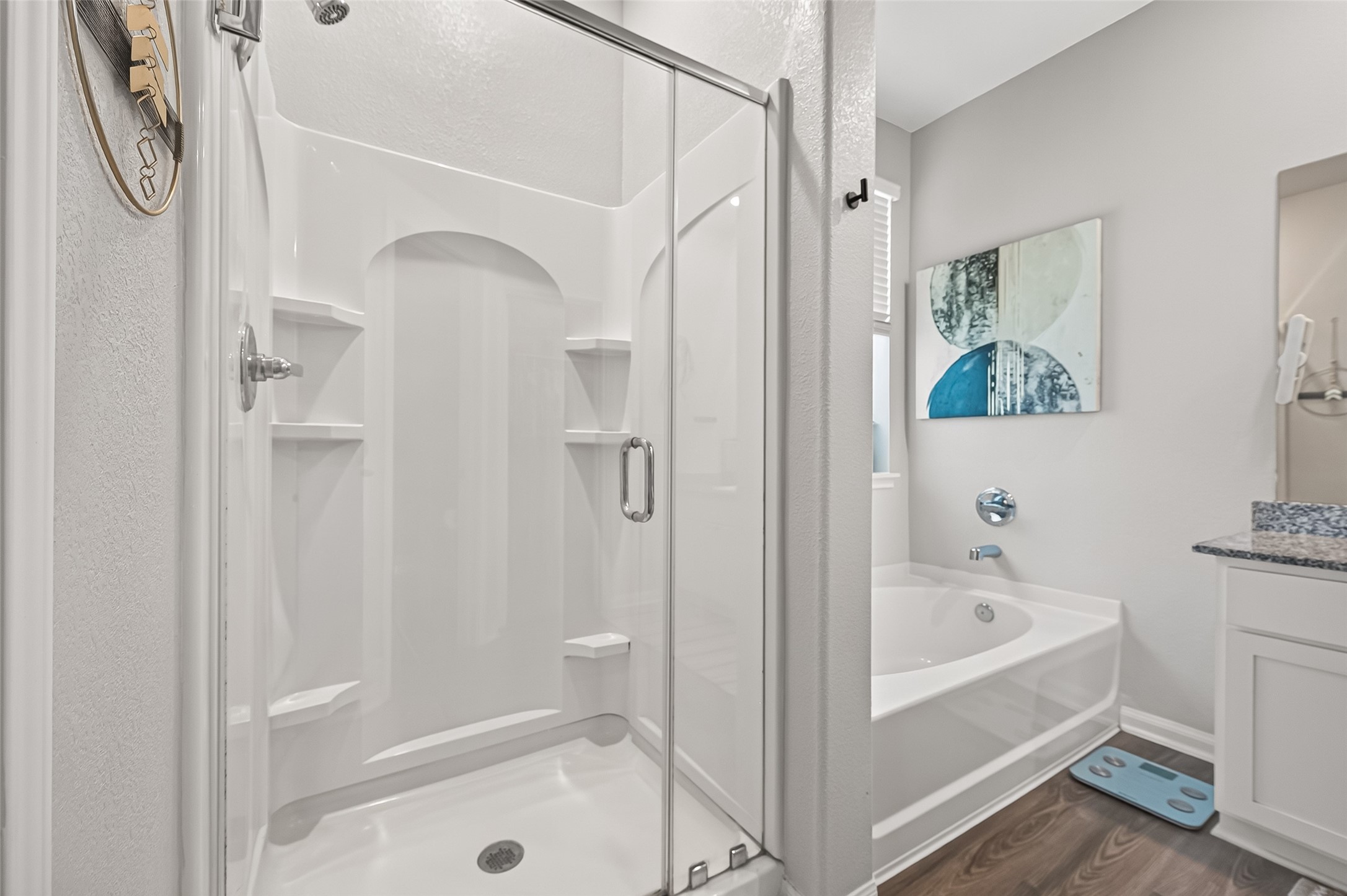 Elegant bathroom featuring a spacious walk-in shower with glass doors, a soothing bathtub, and modern fixtures, complemented by stylish decor and granite countertops.
