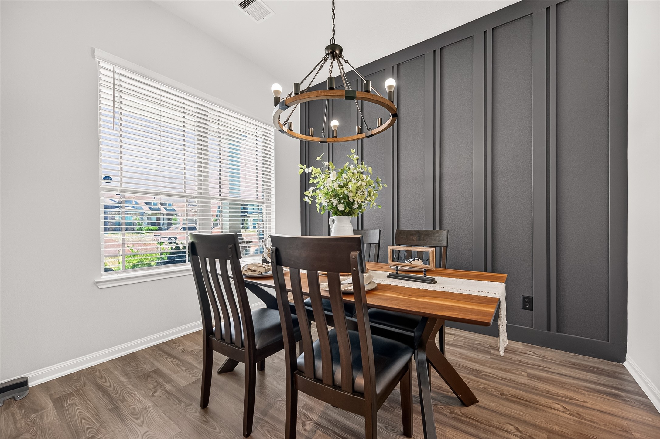 Charming dining area with a modern chandelier, featuring a stylish wood accent wall and large window for natural light. Charming dining area with a modern chandelier, featuring a stylish wood accent wall and large window for natural light.