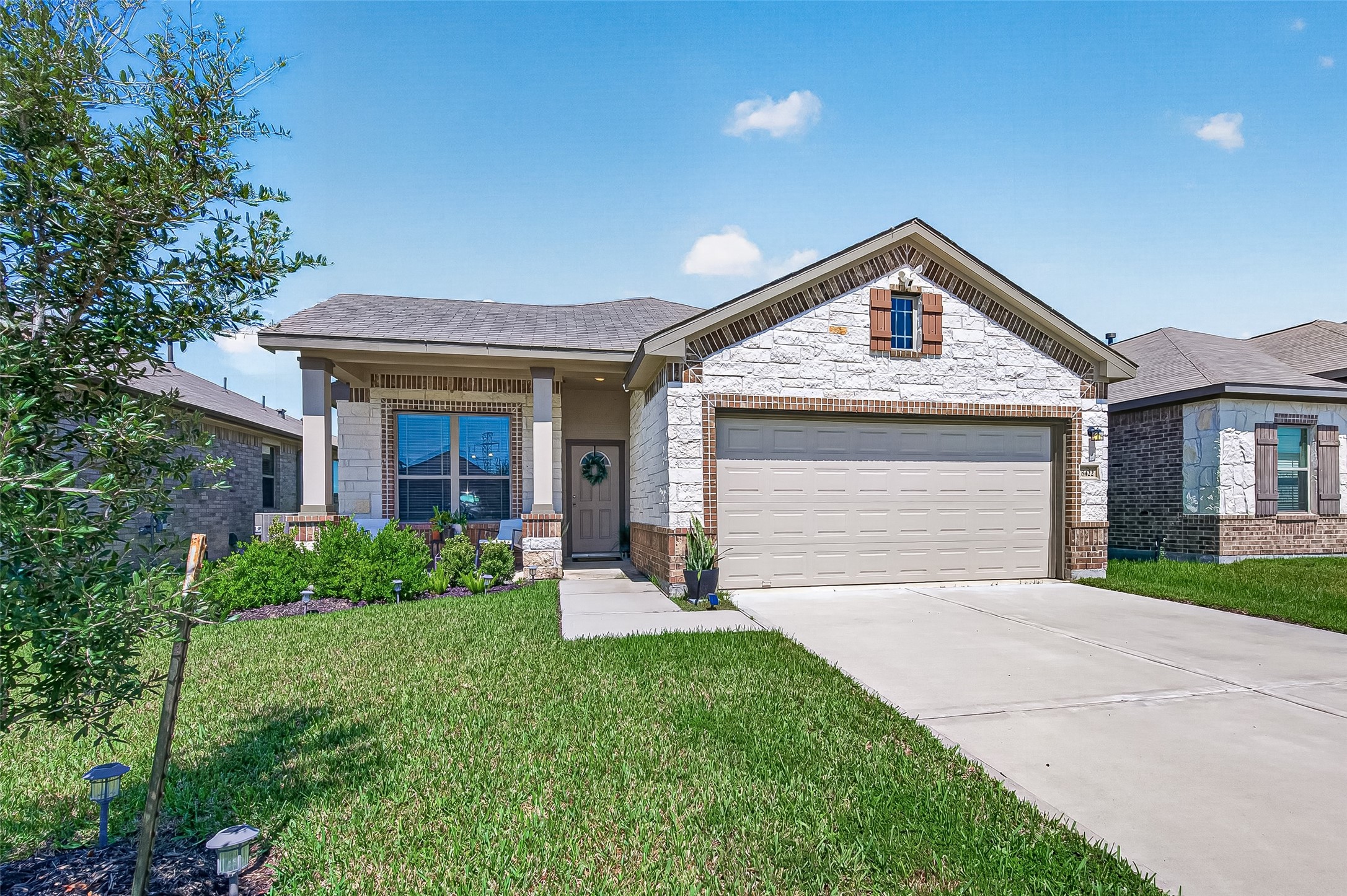 Charming single-story home with a welcoming front porch, neatly manicured lawn, and a spacious two-car garage.