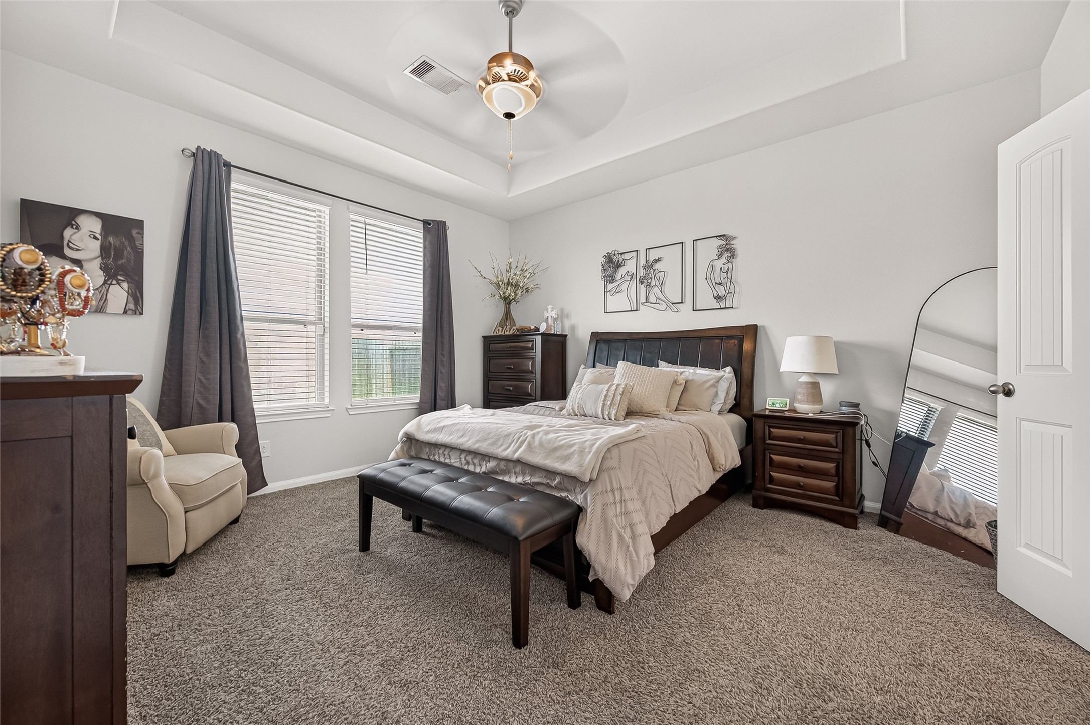 Spacious and inviting bedroom with plush carpeting, featuring a cozy bed, elegant furnishings, and abundant natural light from large windows.