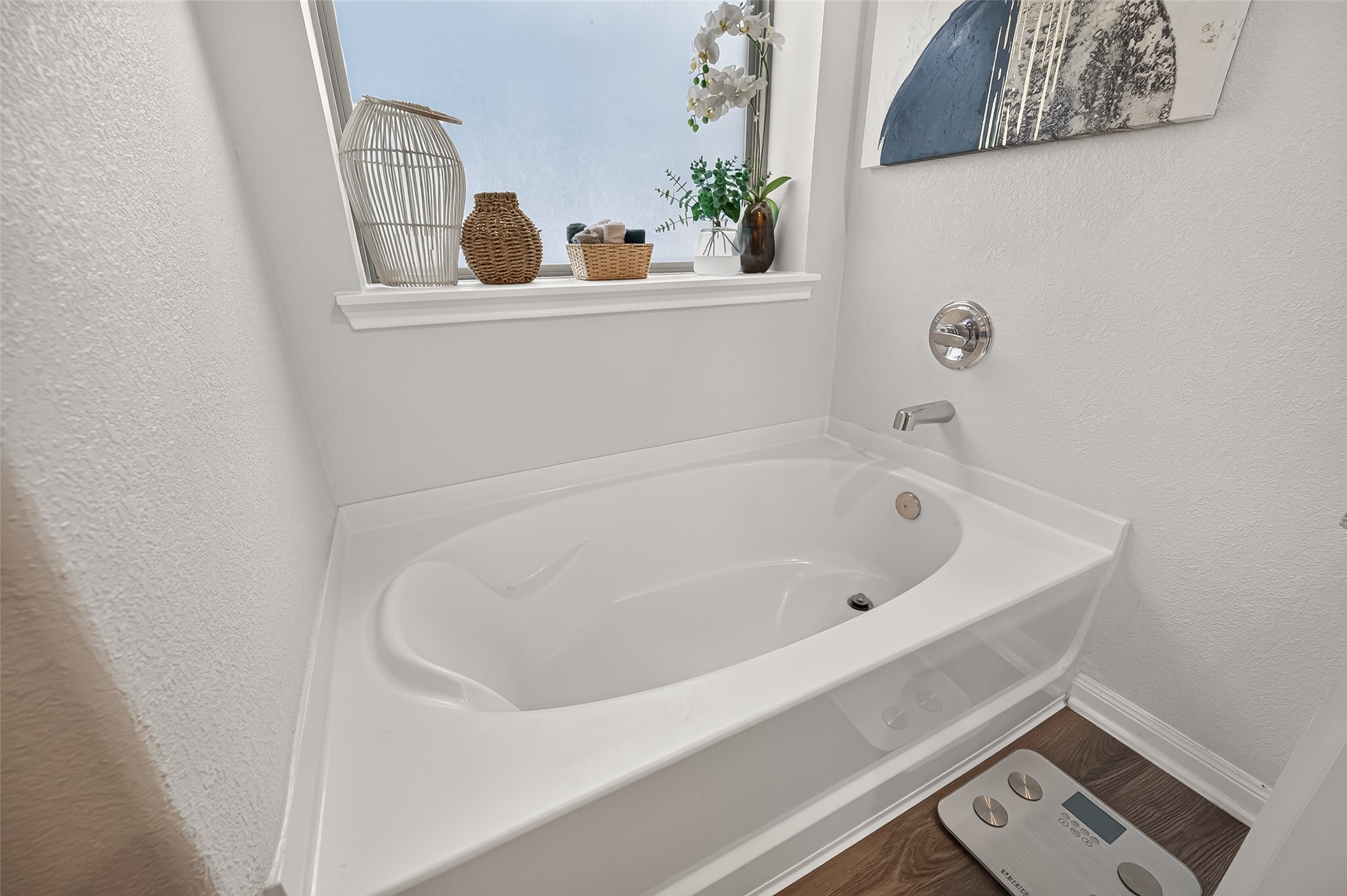 Relax in this bright bathroom featuring a sleek soaking tub, a stylish window sill with decorative accents, and modern fixtures.