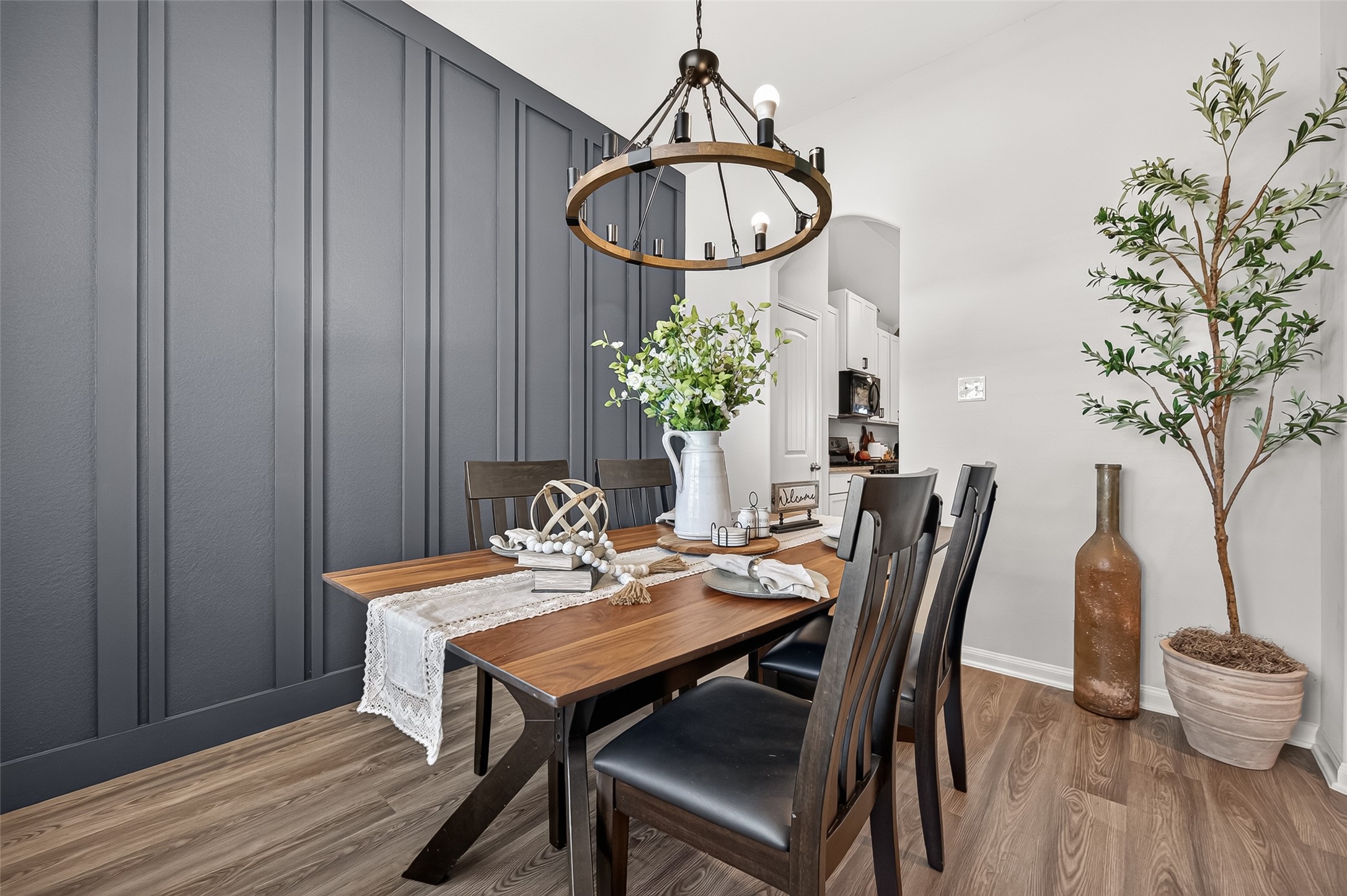 Elegant dining area featuring a stylish wood table, modern chandelier, and a striking dark paneled accent wall. Elegant dining area featuring a stylish wood table, modern chandelier, and a striking dark paneled accent wall.