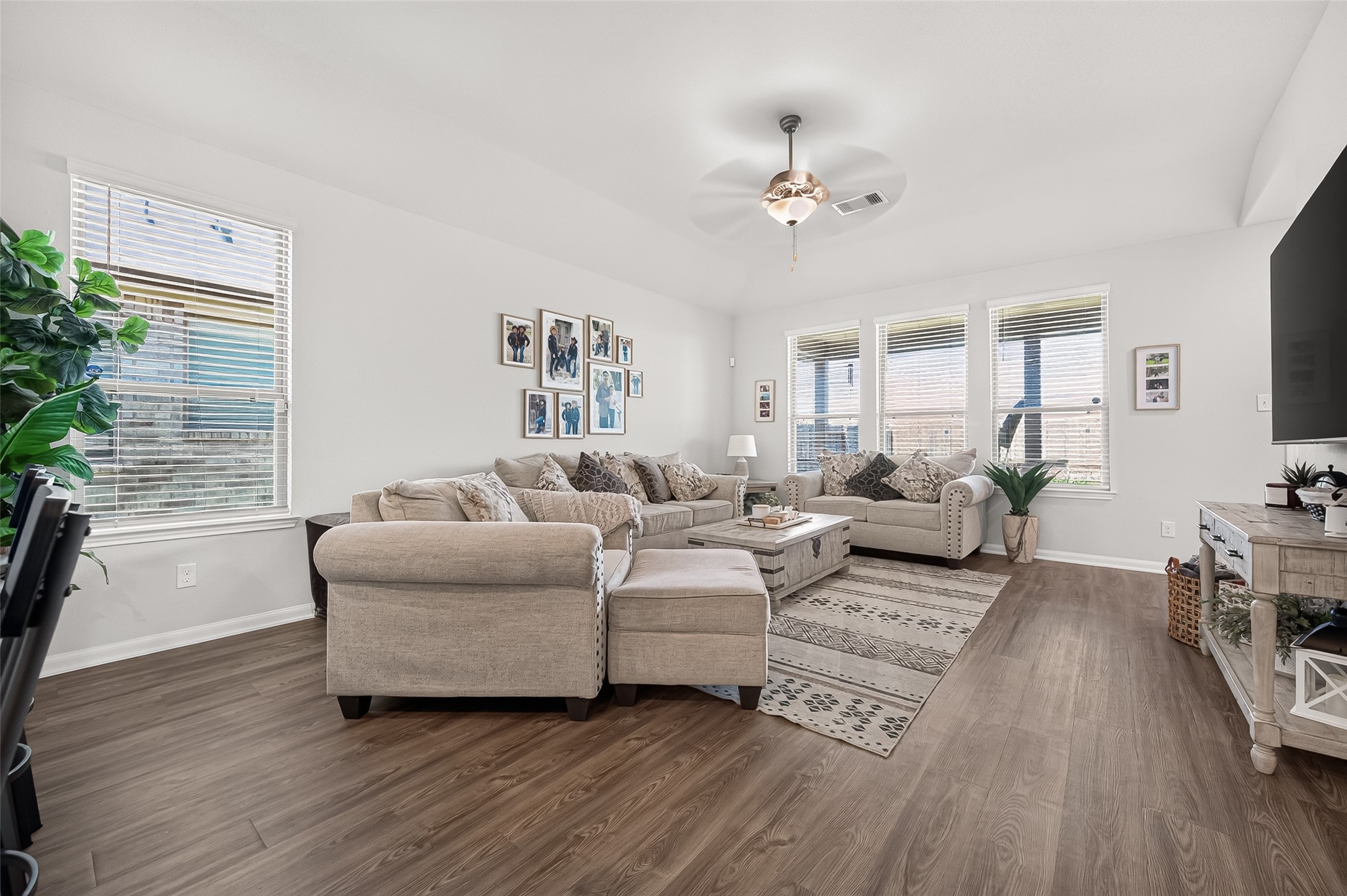 Bright and inviting living room with large windows, stylish hardwood floors, and comfortable seating, perfect for relaxation and entertaining.
