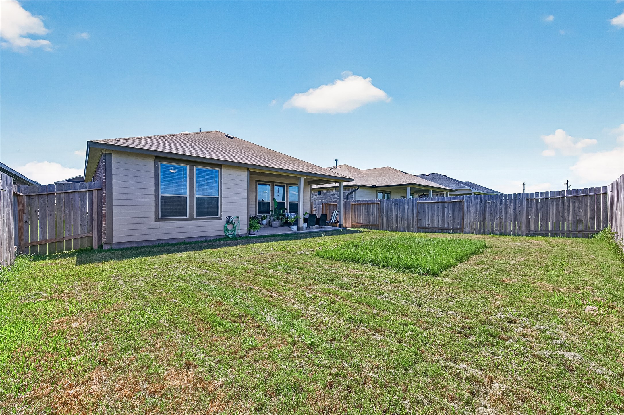 Spacious backyard with well-maintained lawn, privacy fence, and a cozy covered patio perfect for outdoor relaxation and entertaining.