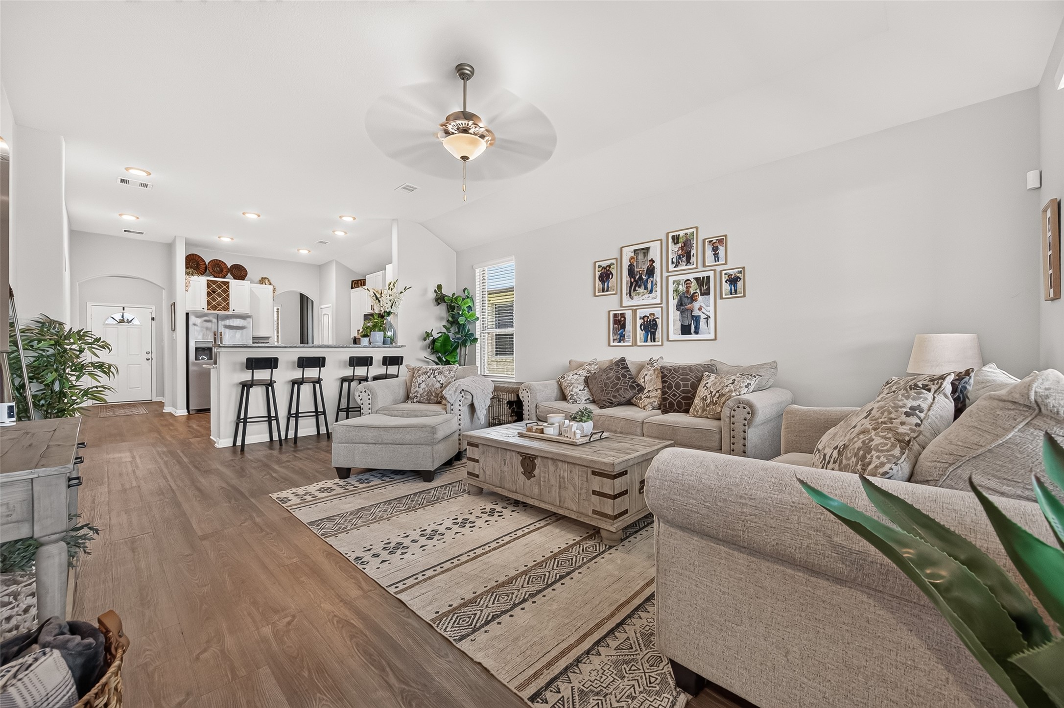 Spacious open-concept living area with elegant hardwood floors, cozy seating, and a stylish kitchen featuring a breakfast bar with modern stools.