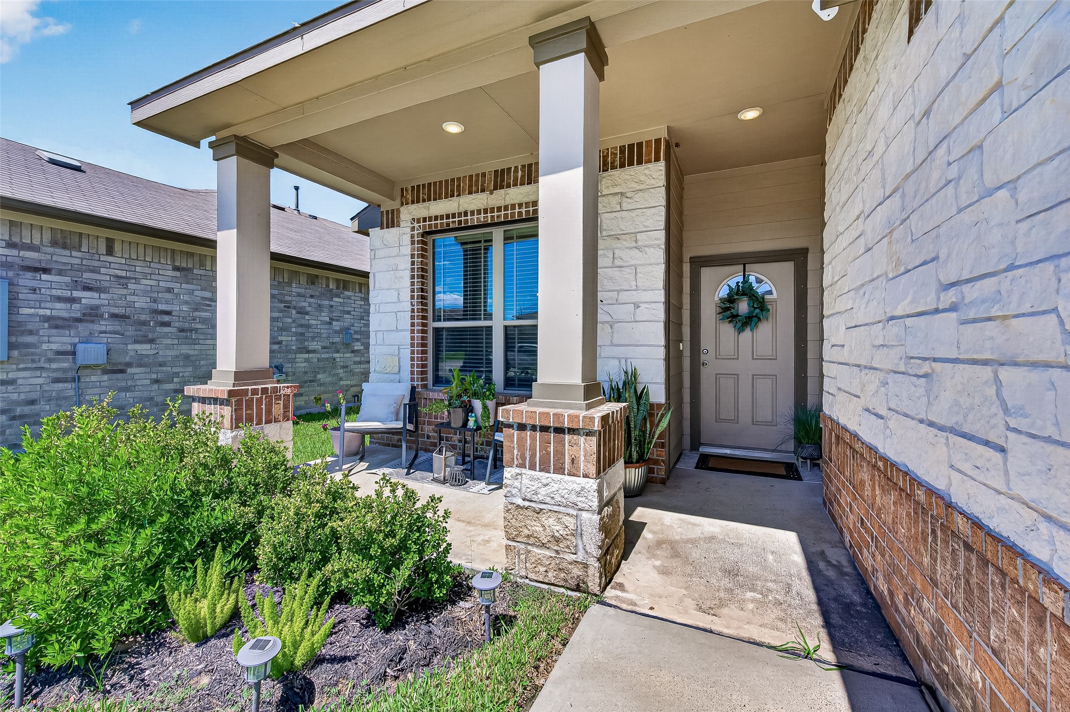 Charming front porch with elegant stone accents, inviting seating area, and lush greenery, offering a warm and welcoming entrance. Charming front porch with elegant stone accents, inviting seating area, and lush greenery, offering a warm and welcoming entrance.