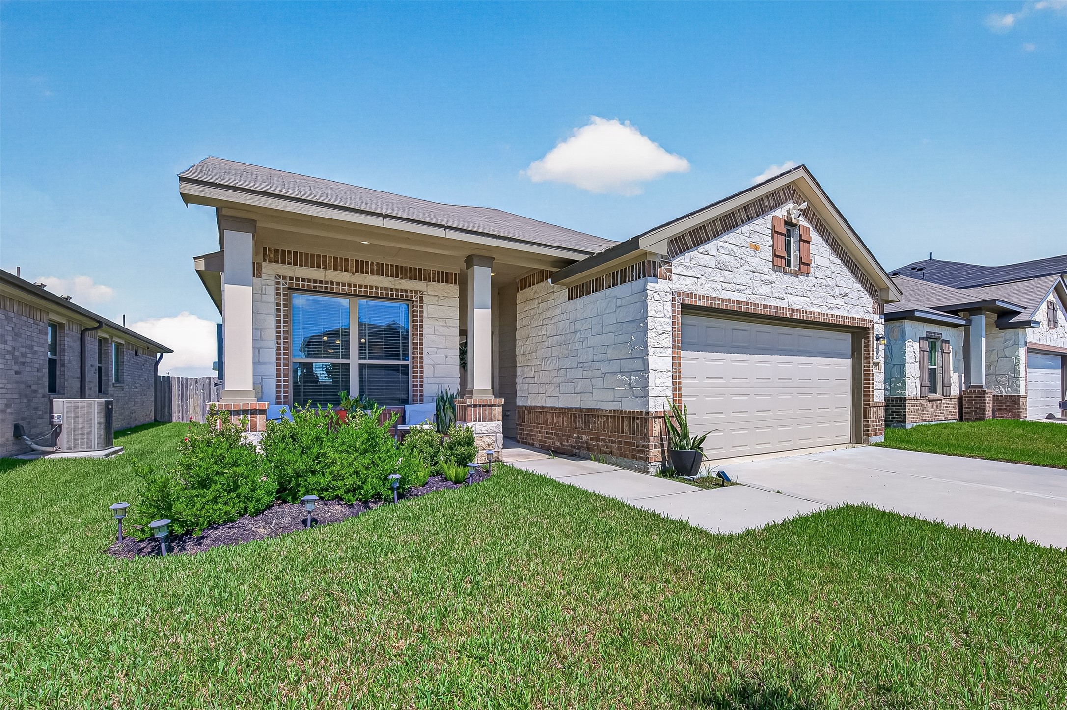 Charming single-story home with a welcoming front porch, elegant brick and stone facade, and well-manicured landscaping. Charming single-story home with a welcoming front porch, elegant brick and stone facade, and well-manicured landscaping.