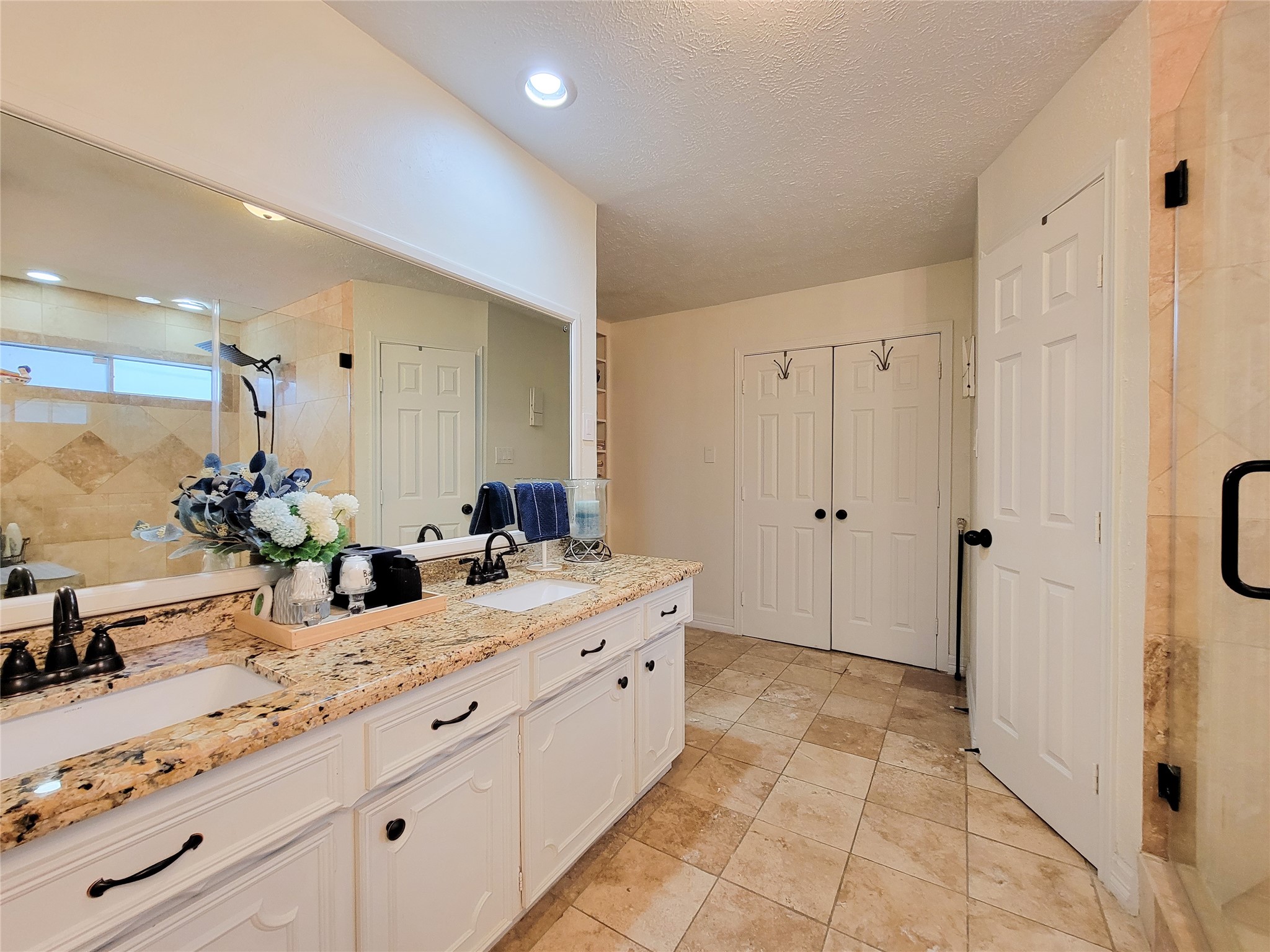 This spacious bathroom features a dual-sink vanity with elegant granite countertops, ample storage, and a large mirror. It has a modern shower with glass doors, tiled flooring, and soft, neutral tones throughout, creating a serene atmosphere. This spacious bathroom features a dual-sink vanity with elegant granite countertops, ample storage, and a large mirror. It has a modern shower with glass doors, tiled flooring, and soft, neutral tones throughout, creating a serene atmosphere.
