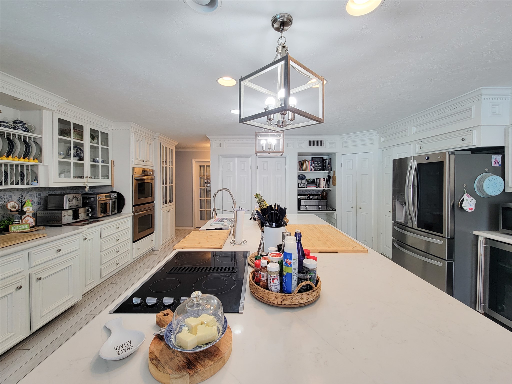 Bright and spacious kitchen with modern appliances, ample cabinet storage, and a large central island perfect for cooking and entertaining. Elegant lighting and a clean, white aesthetic enhance the inviting atmosphere.