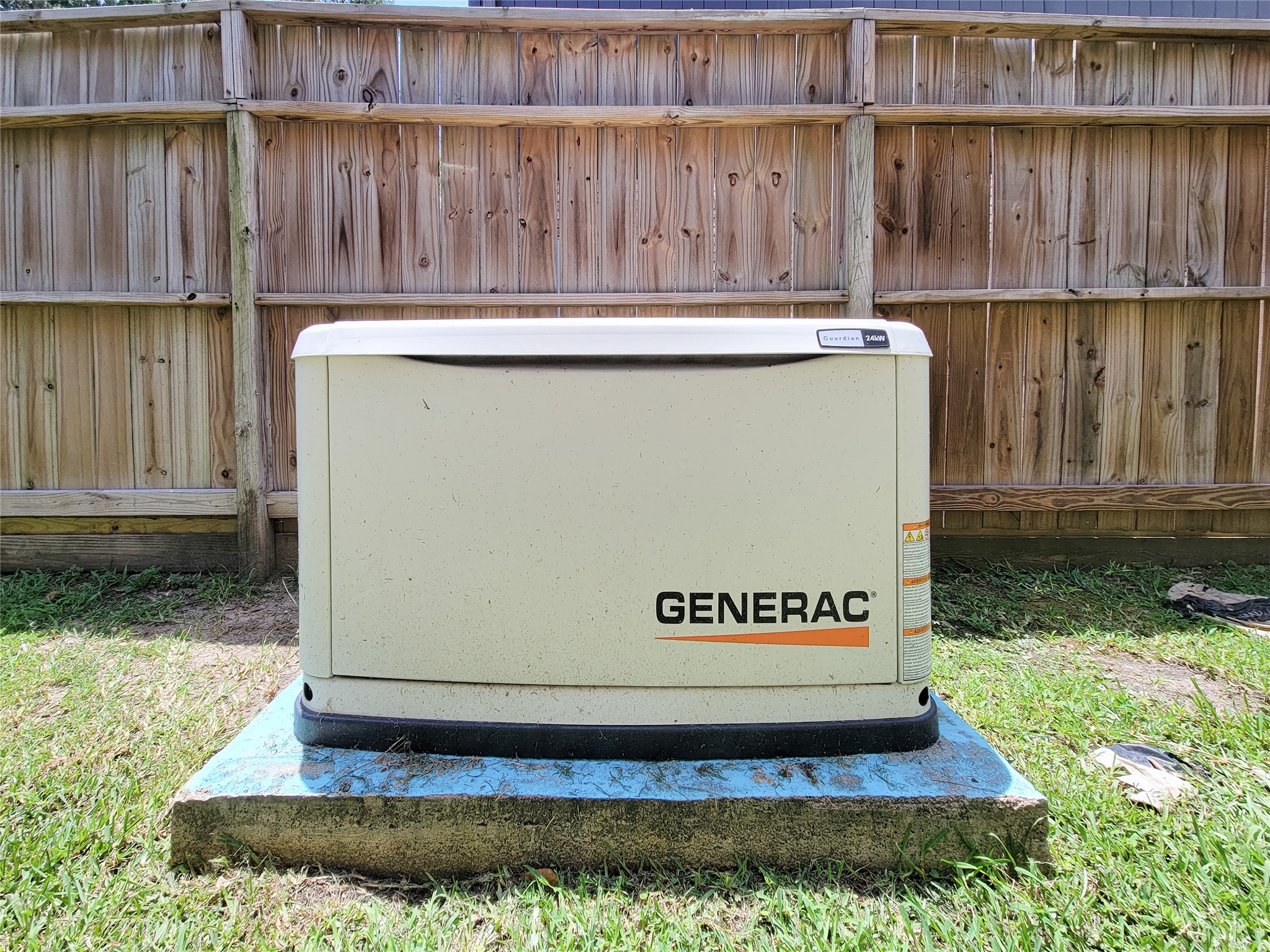 This photo shows a Generac standby generator installed on a concrete pad in a backyard, providing backup power capability for the home.