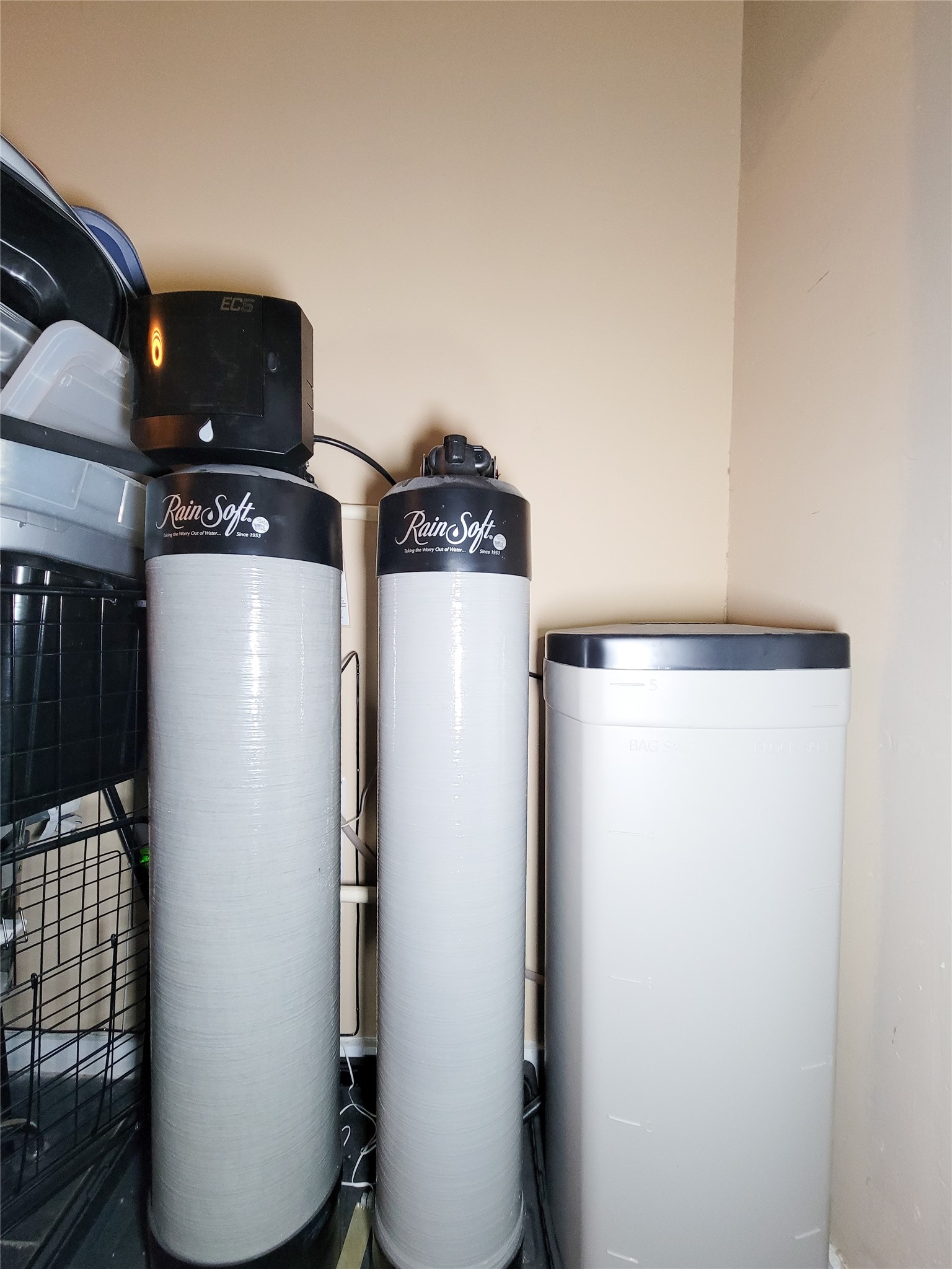 Water softening system, including two RainSoft tanks and a brine tank, installed in a utility area.