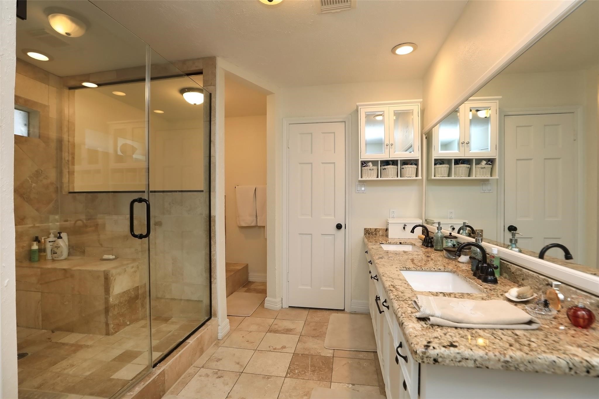 This bathroom features a spacious walk-in glass shower with elegant tile work, dual sinks with granite countertops, and ample storage. It offers a clean, modern aesthetic with warm lighting. This bathroom features a spacious walk-in glass shower with elegant tile work, dual sinks with granite countertops, and ample storage. It offers a clean, modern aesthetic with warm lighting.