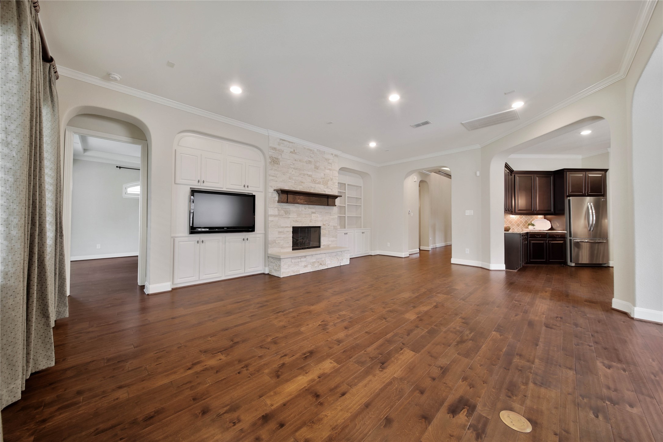 The spacious living area is designed for comfort and style, featuring a built-in entertainment center and a beautiful floor-to-ceiling stone gas log fireplace that anchors the room.