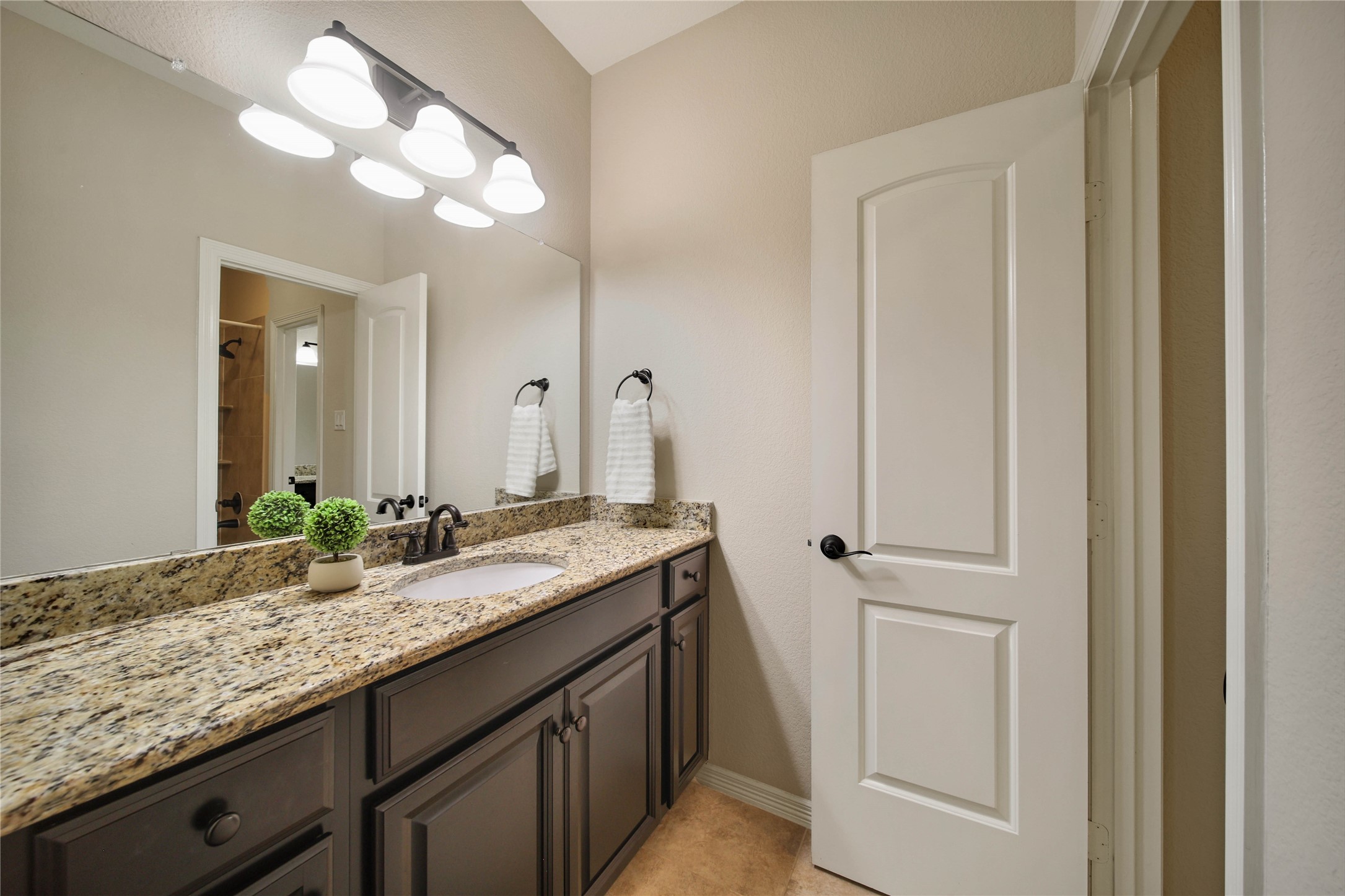 Private vanity leads into a shared bathroom with shower/tub combo.