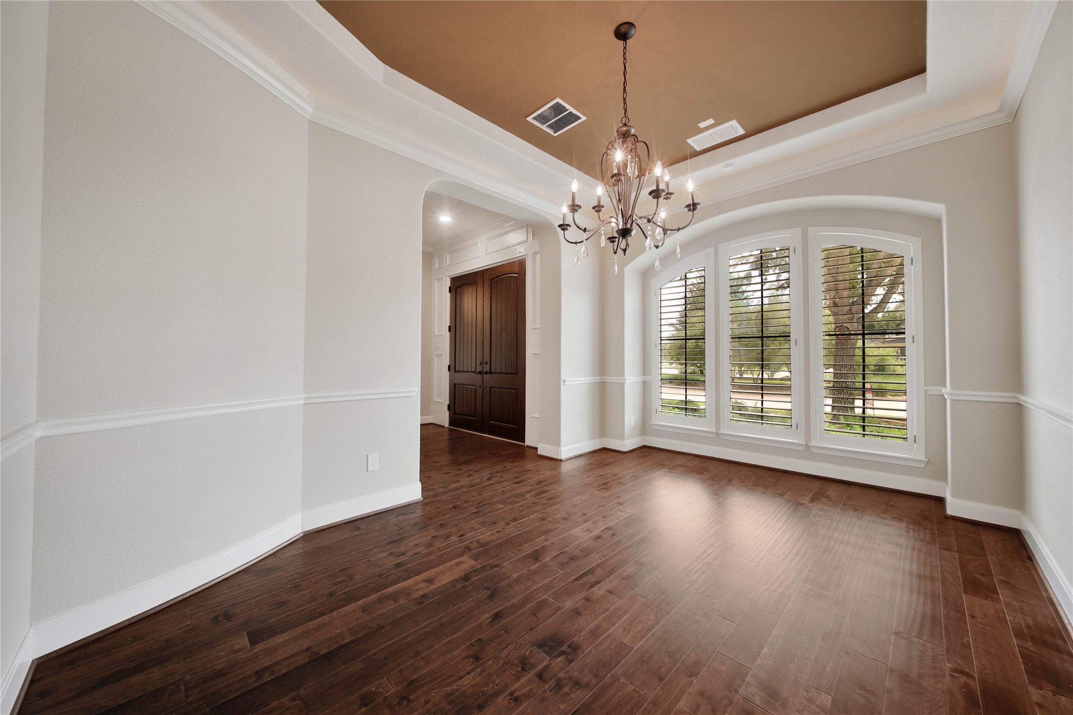 Designed for entertaining, the formal dining room showcases warm wood floors, plantation shutters, and a stunning tray ceiling highlighted by soft rope lighting.