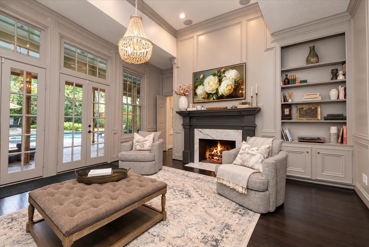 Made for entertaining and everyday comfort, this spacious living room has room for large gatherings, an elegant fireplace mantel to anchor the space, and French doors that lead straight out to the covered patio and pool.